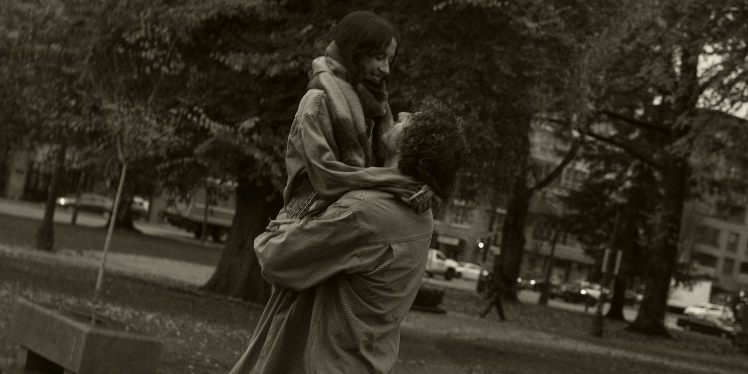 A romantic couple embraces on a city street in vintage-style photography.