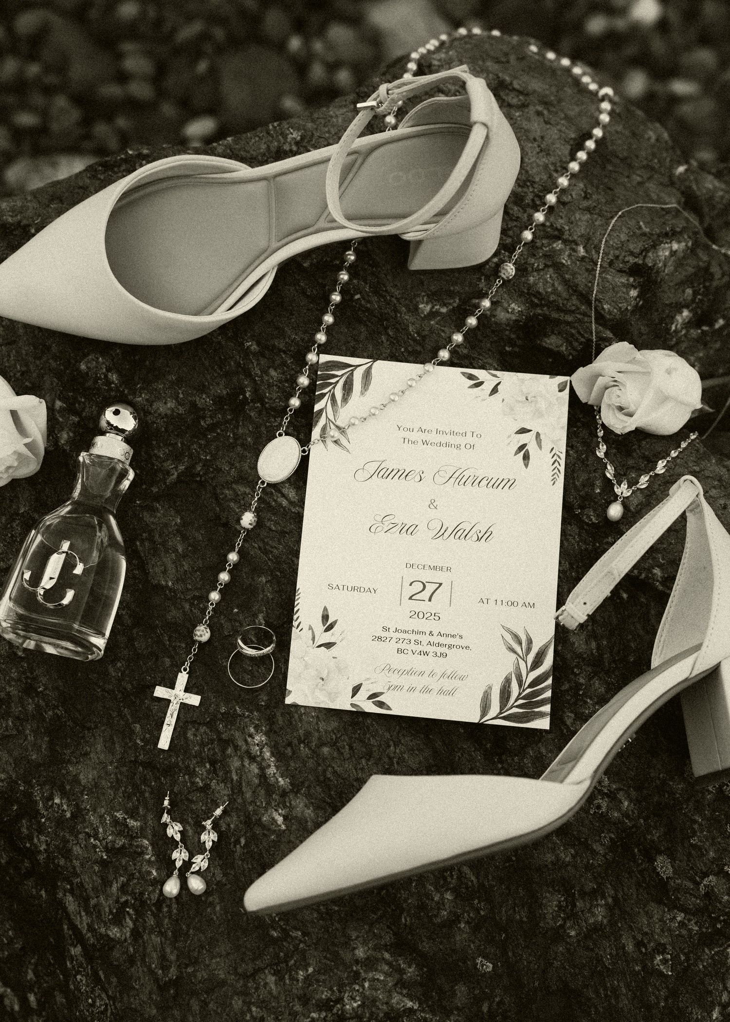 Wedding details flatlay with white heels, pearl rosary, and invitation card on dark textured surface.
