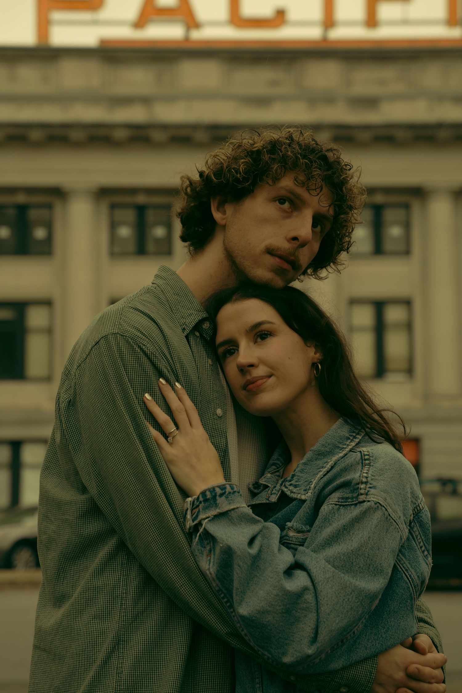 A couple in denim jackets shares a tender moment outdoors.