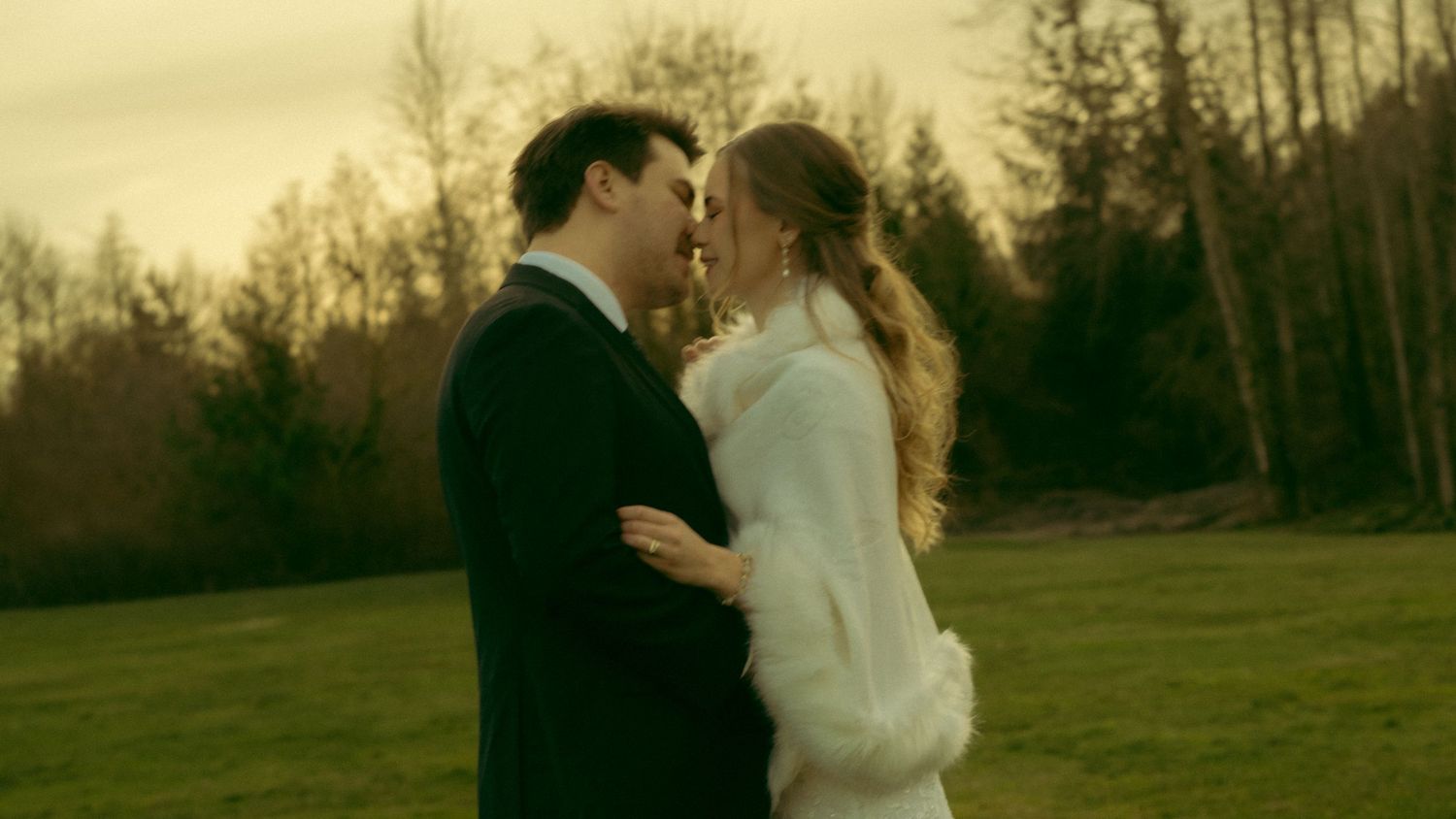 Romantic outdoor wedding portrait against a backdrop of winter trees at sunset.
