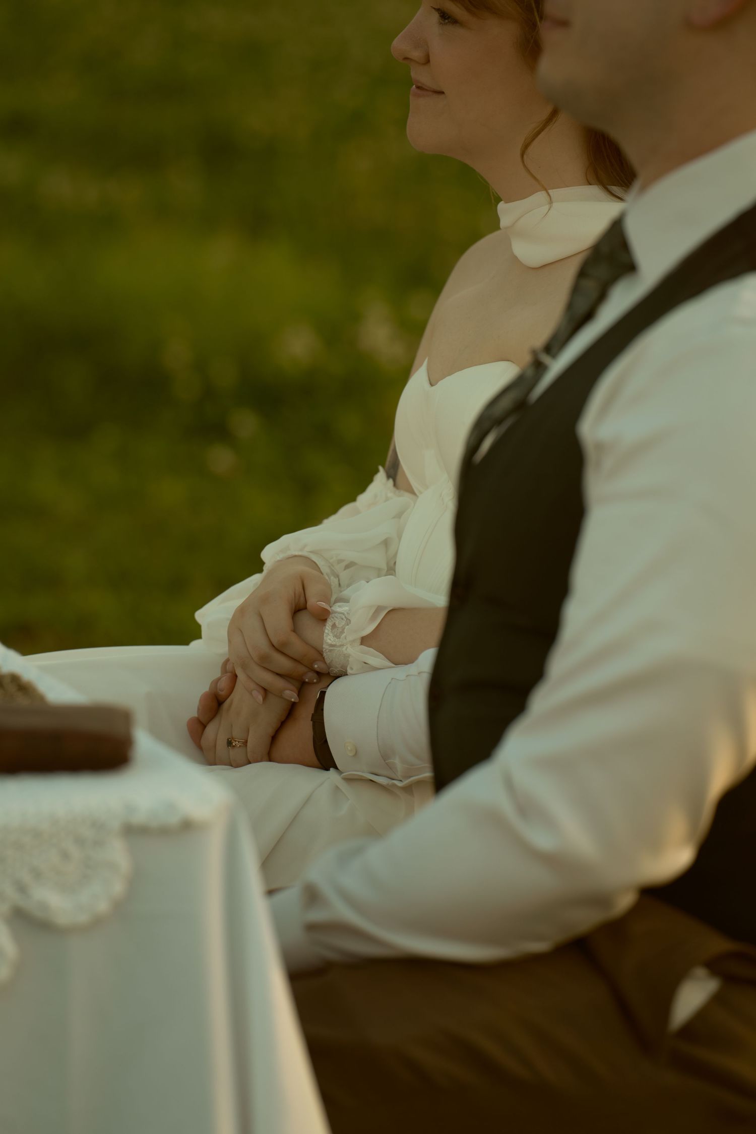 A person in formal attire rests their hands on a white tablecloth at an elegant event.