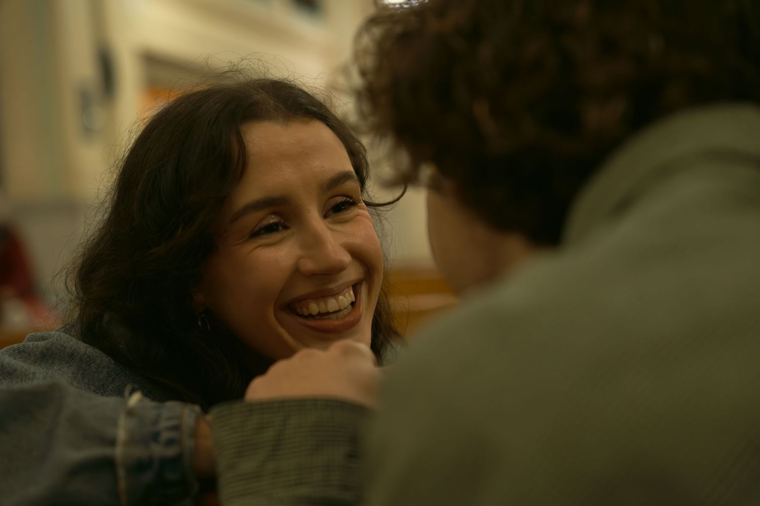 A candid moment captured in warm lighting shows two people engaged in conversation.