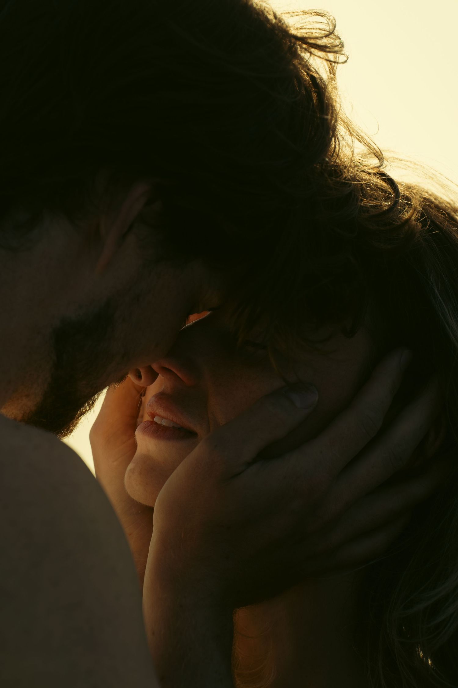 Intimate close-up of couple sharing tender moment in golden light.