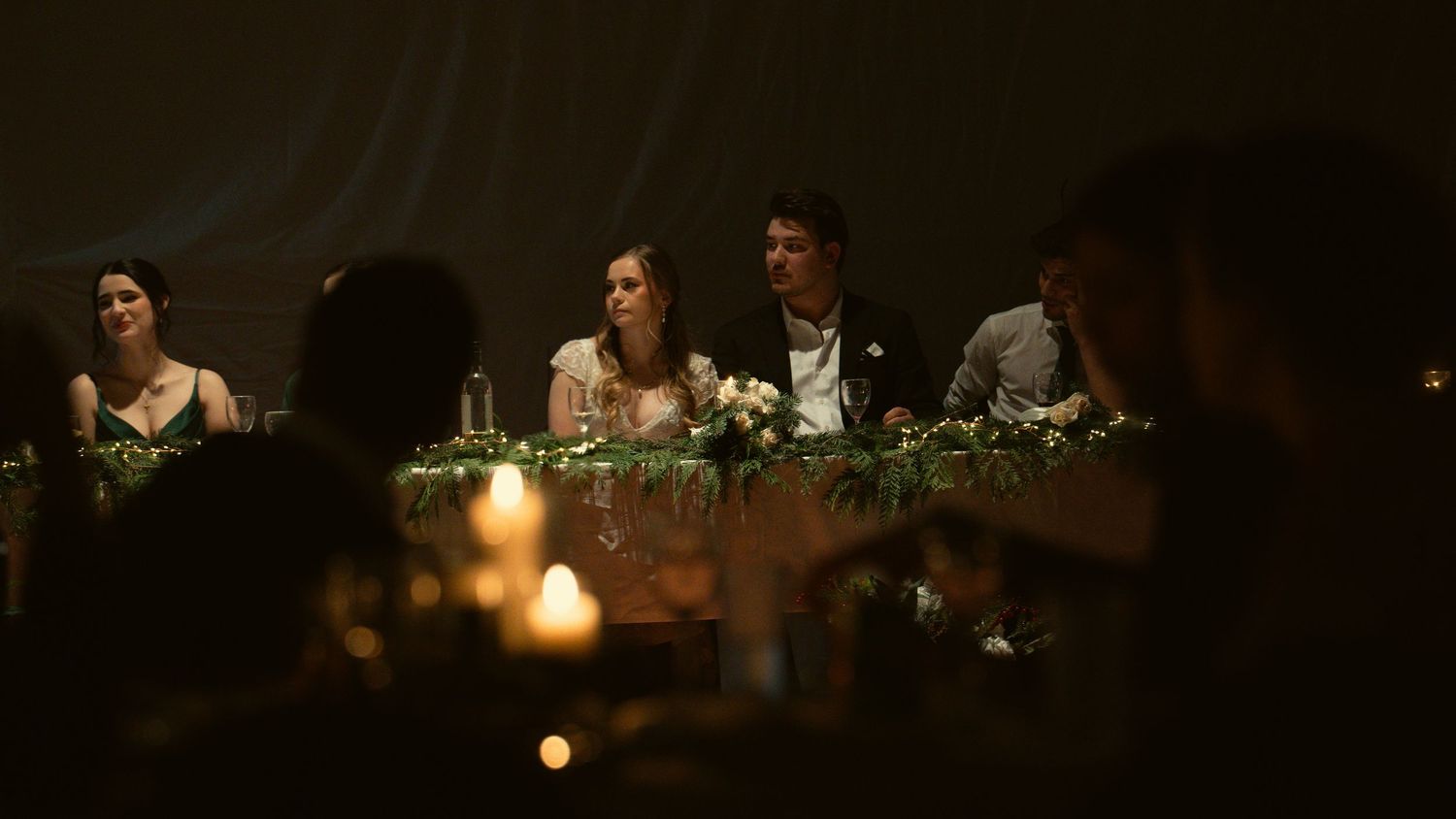 Dimly lit wedding reception with glowing candles and floral centerpieces.
