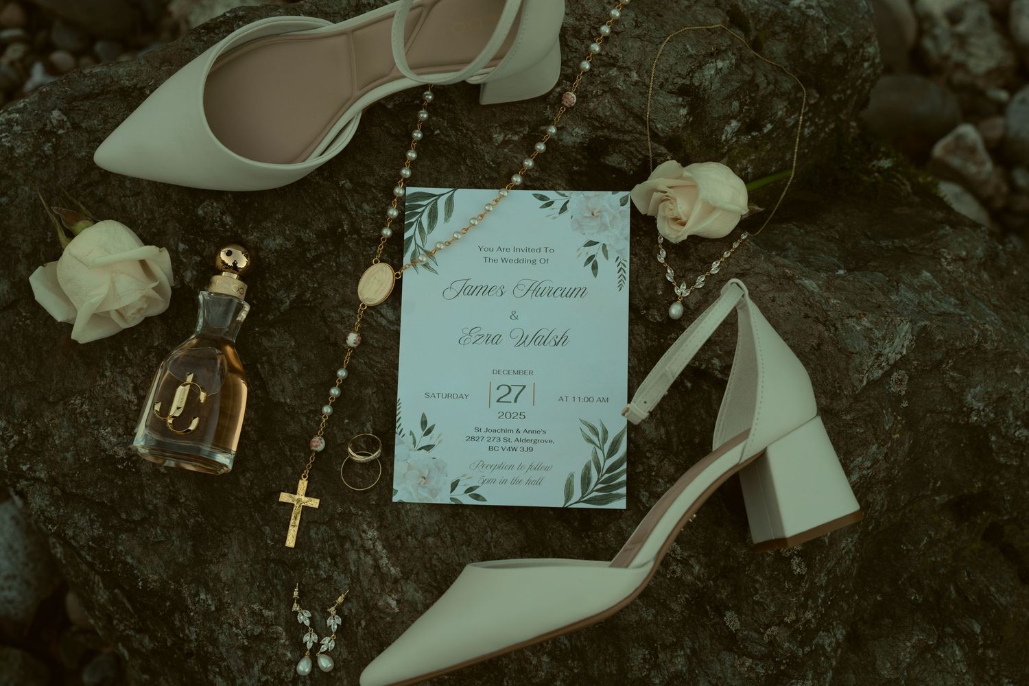 Wedding details flatlay with white heels, blue invitation, rosary beads and small glass bottle on dark background.
