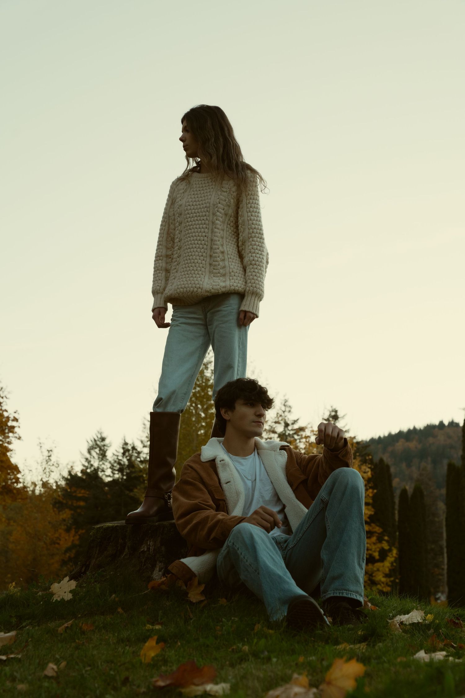 People relaxing on a grassy hill during golden hour with trees in the background.