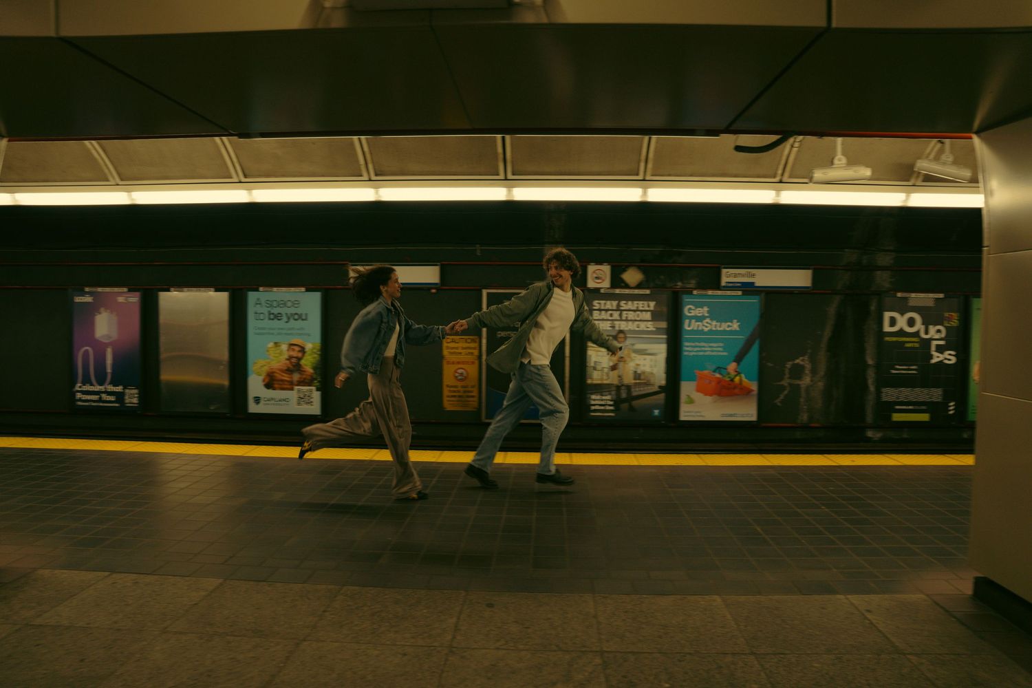 couple, running along a dimly lit subway platform.