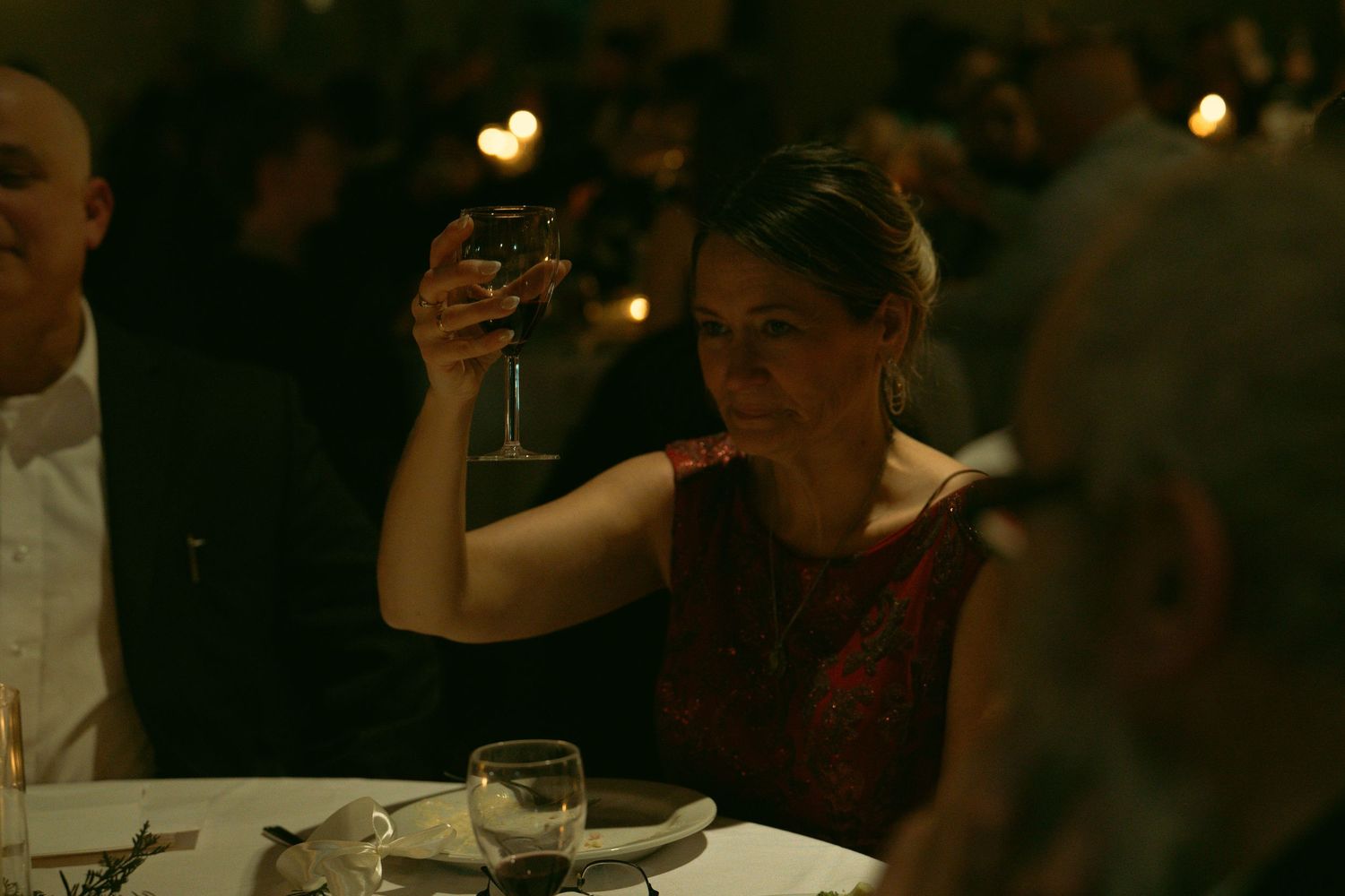 A dimly lit celebration scene with glowing candles and drinks on tables.