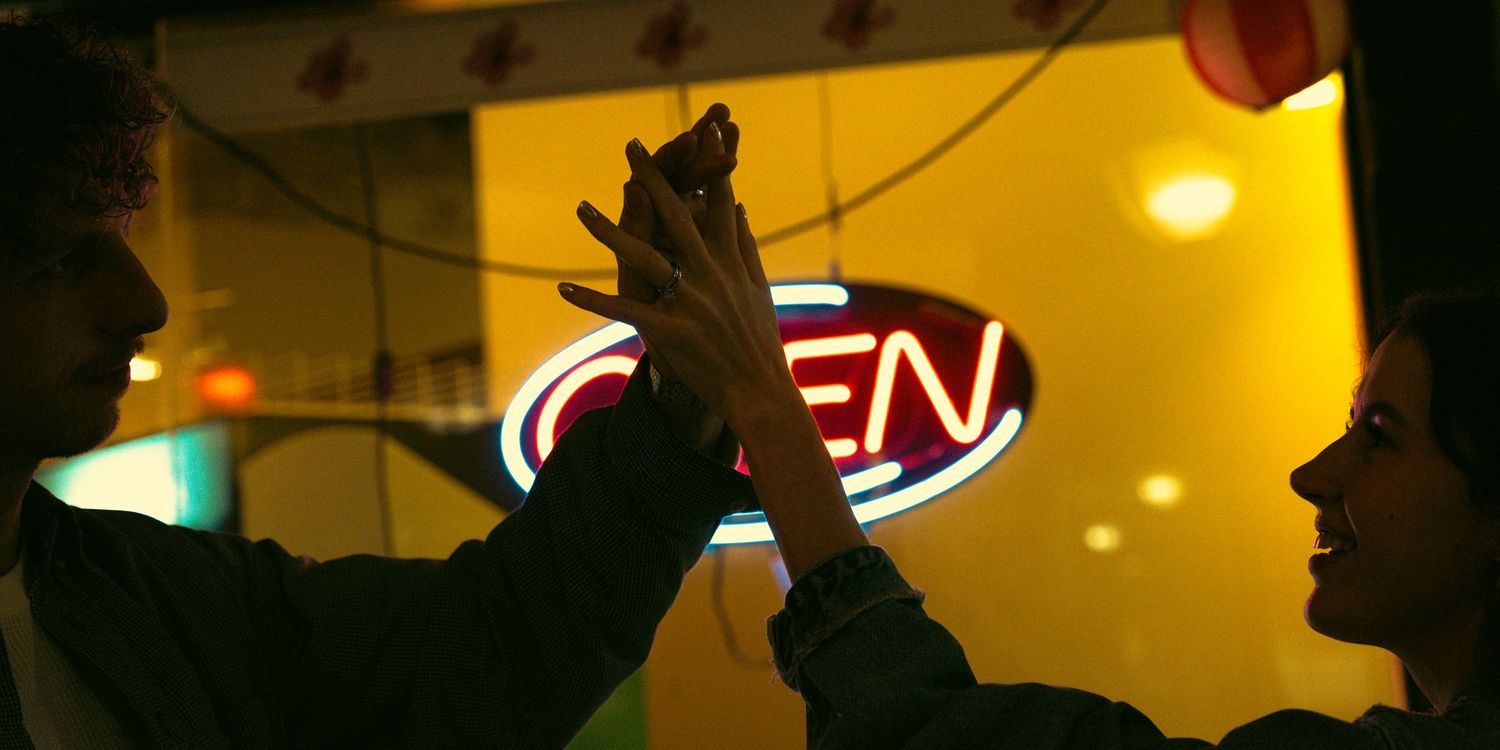 Silhouettes of people against a warm yellow-lit background in an atmospheric setting.