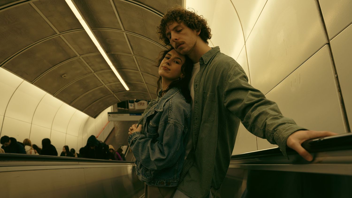 People performing artistic movements in a curved subway tunnel with fluorescent lighting.