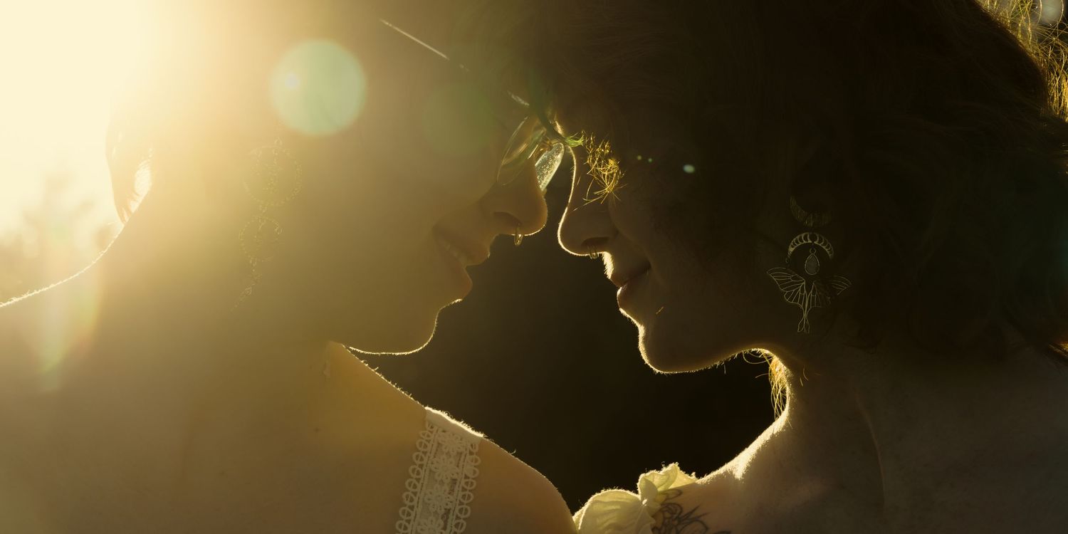 Romantic couple sharing an intimate moment in golden backlit sunlight, silhouetted against a warm glowing bokeh background.