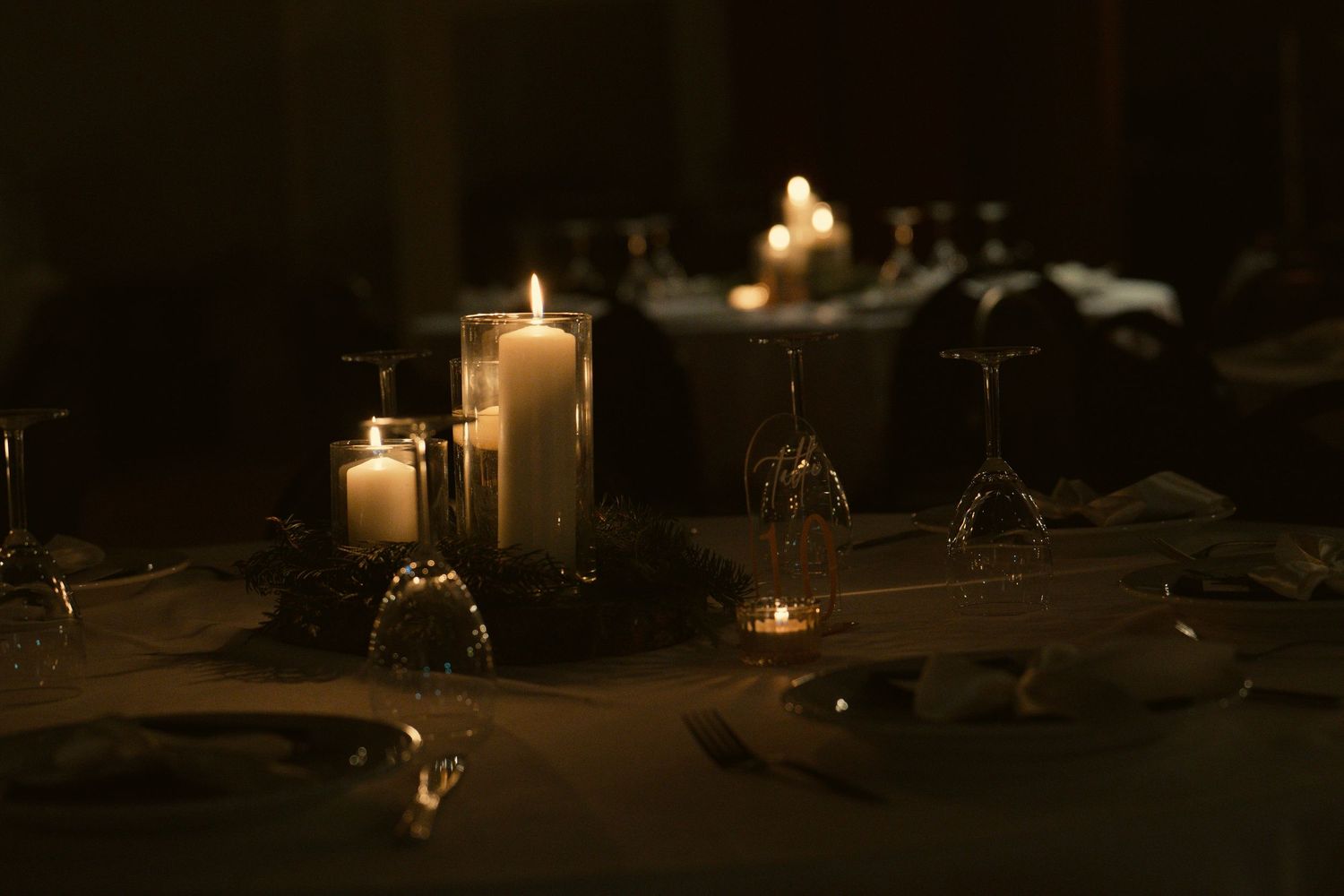 Glowing candles create a romantic atmosphere on a dark reception table.