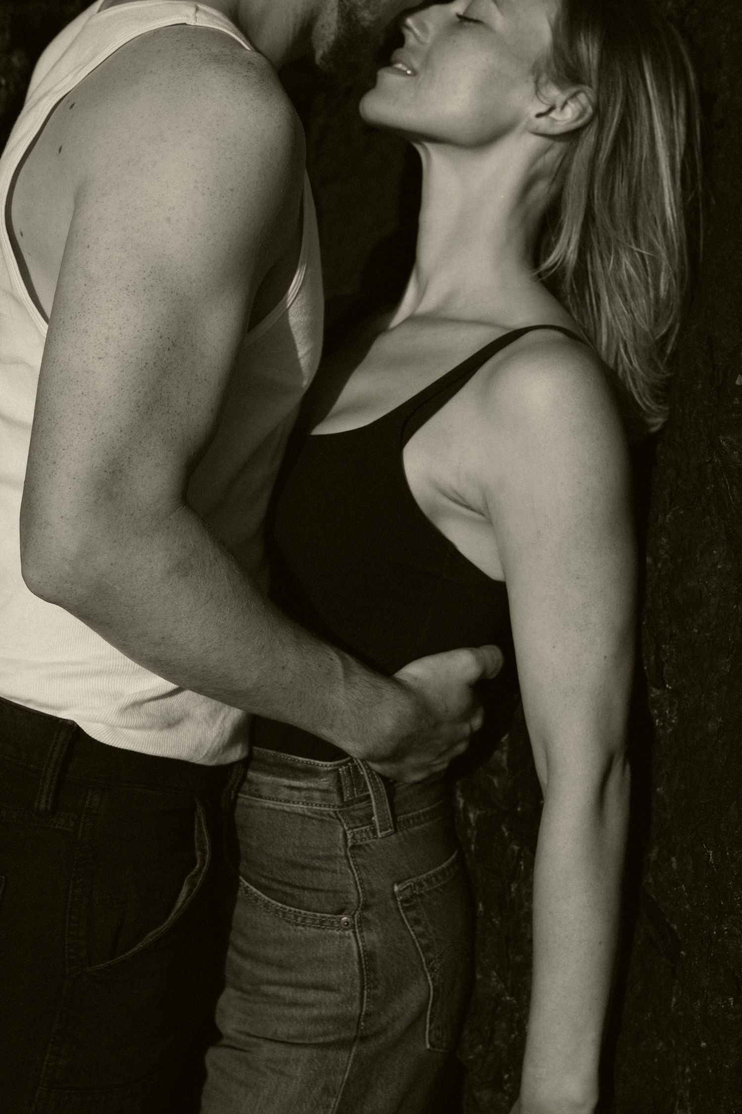 An intimate black and white portrait of a couple in casual attire.
