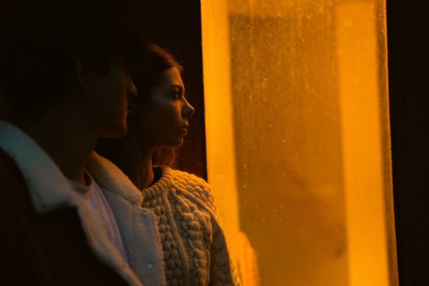 Silhouette of figures against warm orange window light in the evening.