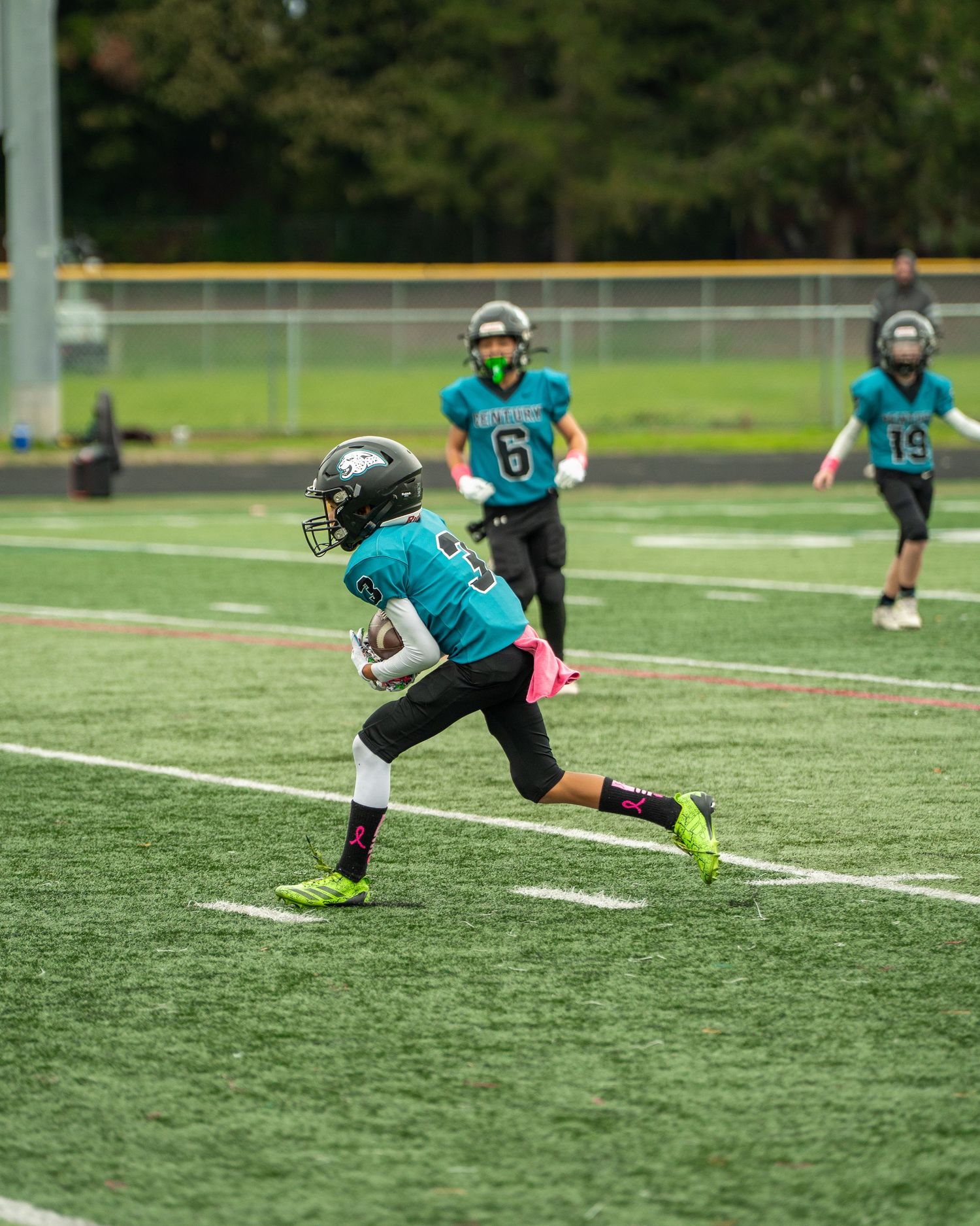 Football player in teal jersey makes diving catch during practice drill.