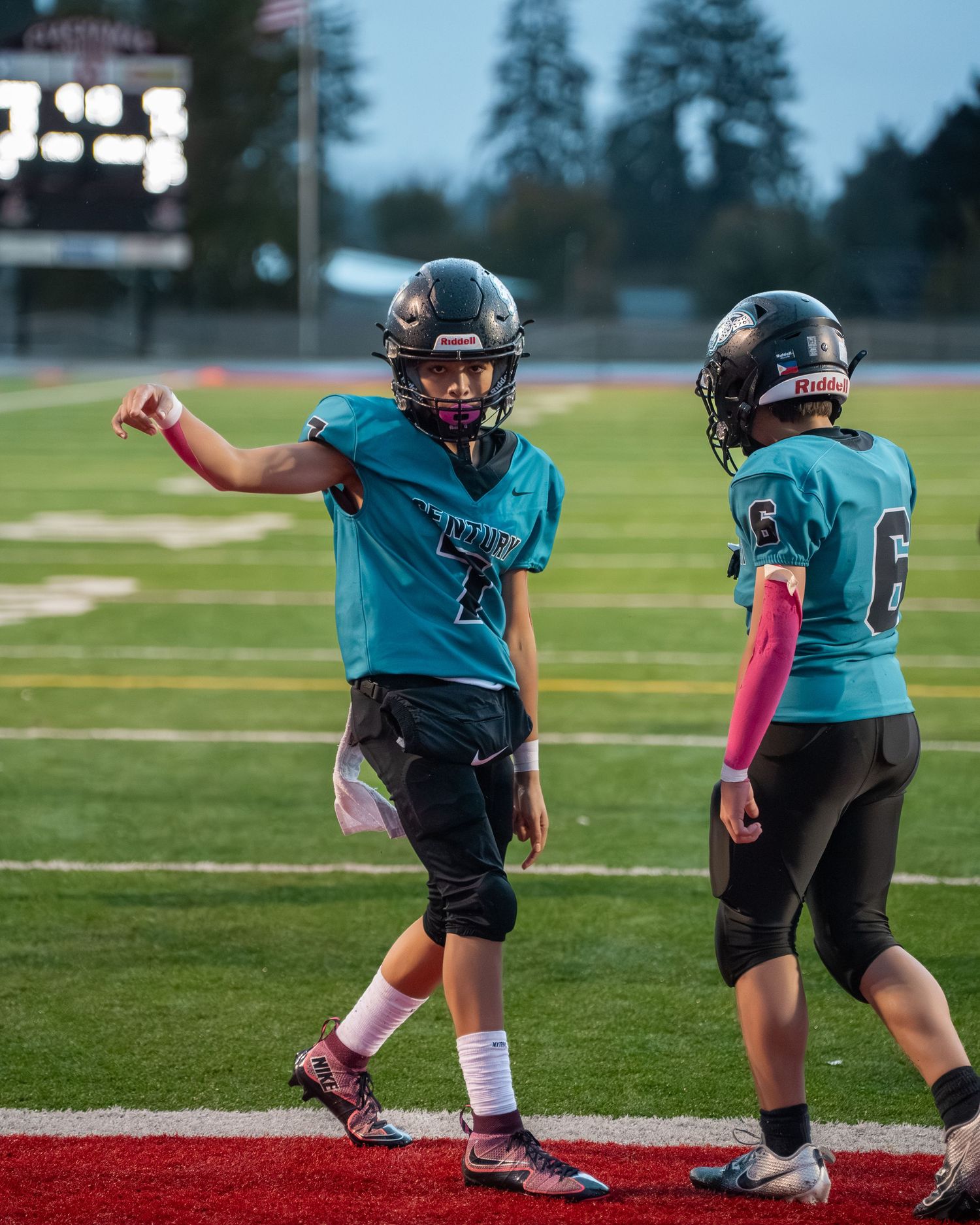 Youth football players in teal jerseys practicing diving drills on field.