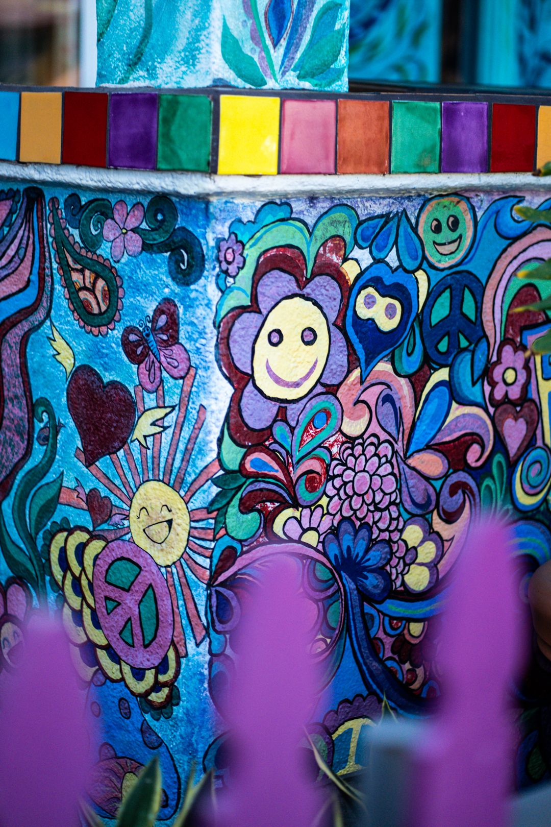 Colorful whimsical mural with cartoon flowers and smiley faces in bright blues and purples.