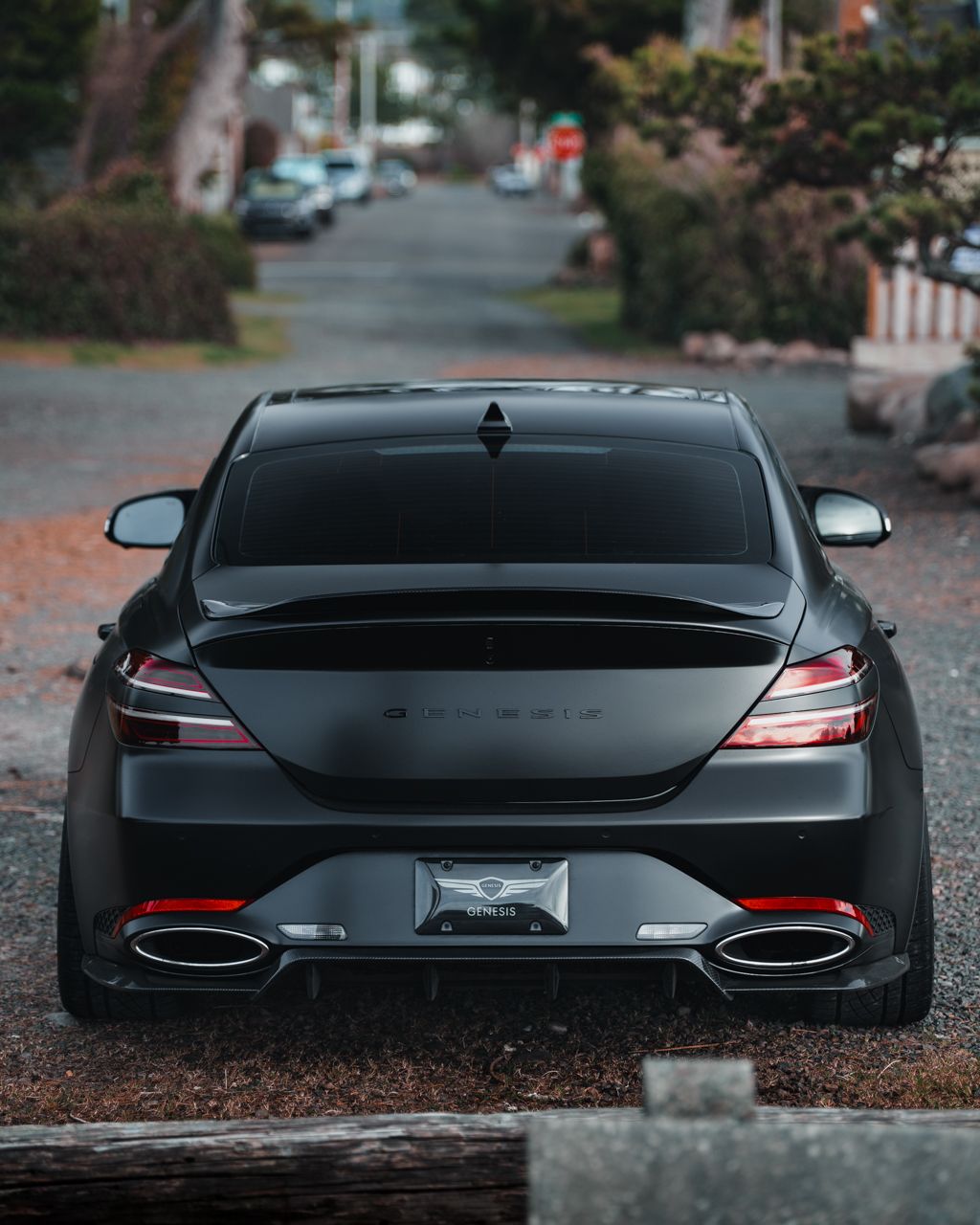 Rear view of a black luxury sedan showing distinctive LED taillights and quad exhaust tips.
