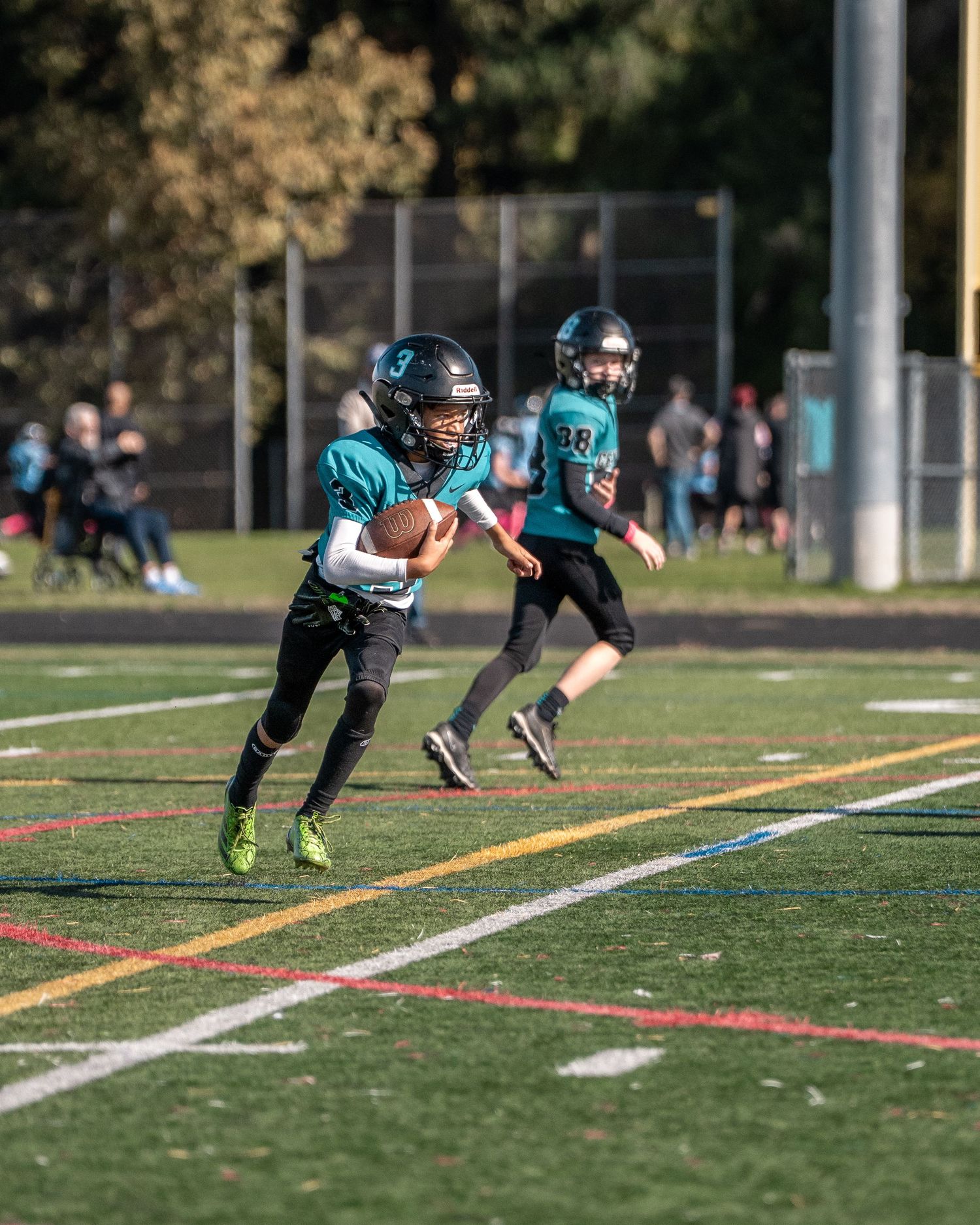 Players in teal uniforms perform diving drills during football practice.
