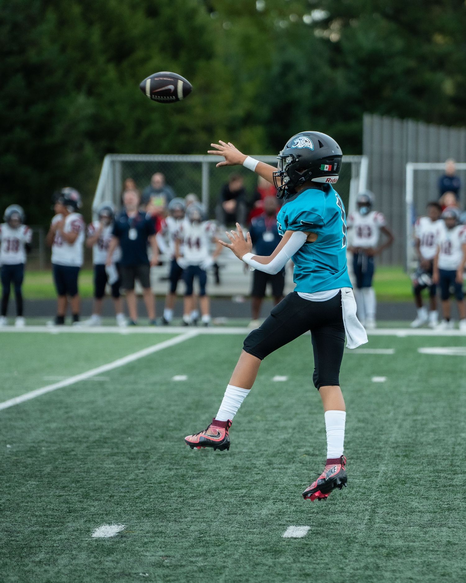 Football player practicing kicking technique on green turf field.