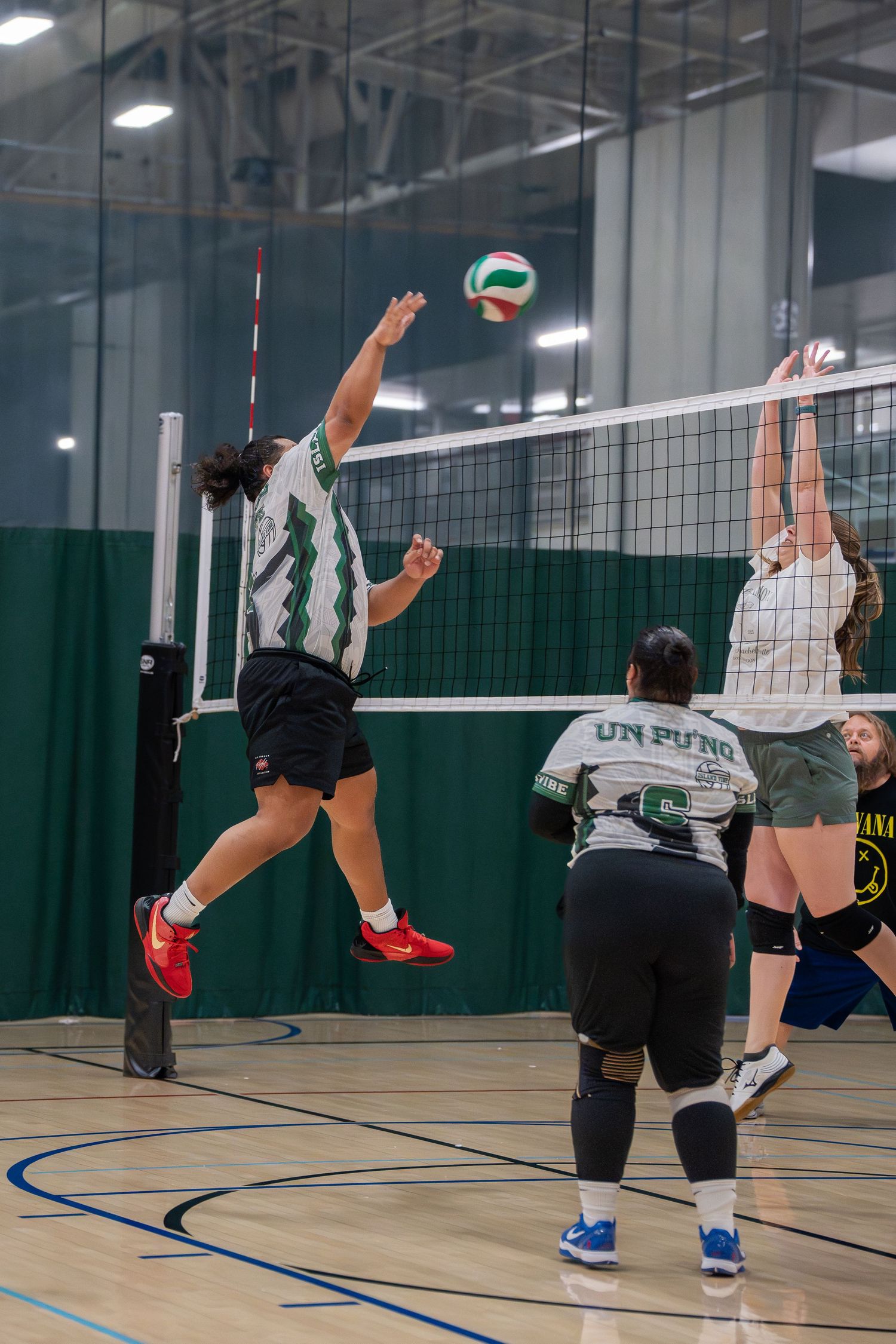 Volleyball players jumping at the net during an intense indoor match.