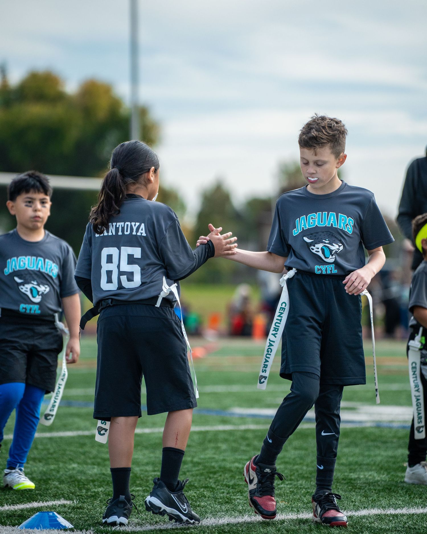 Young athletes in black uniforms standing in a row on an outdoor sports field.