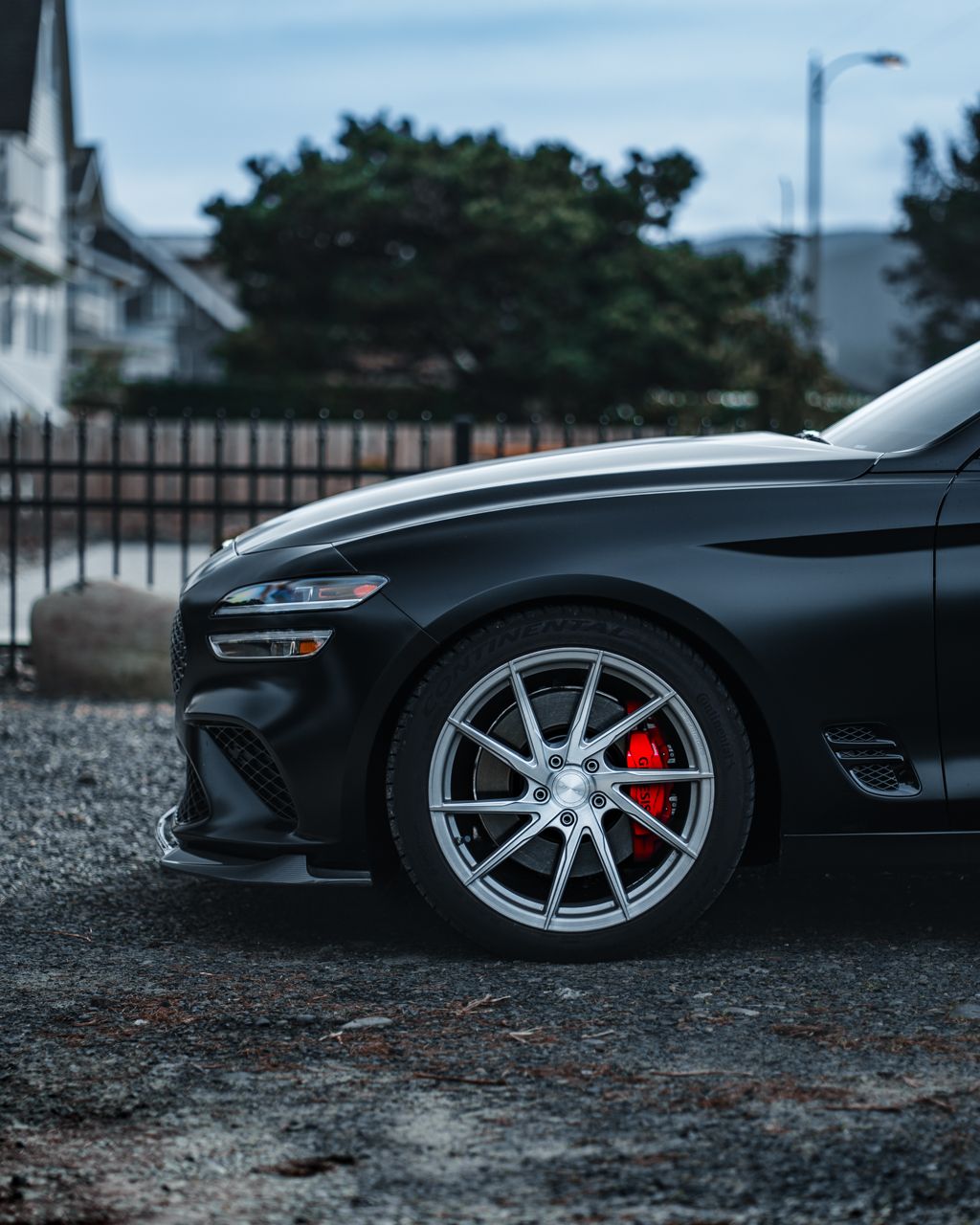 Side profile shots of a lowered black sports car with custom wheels on gravel terrain.