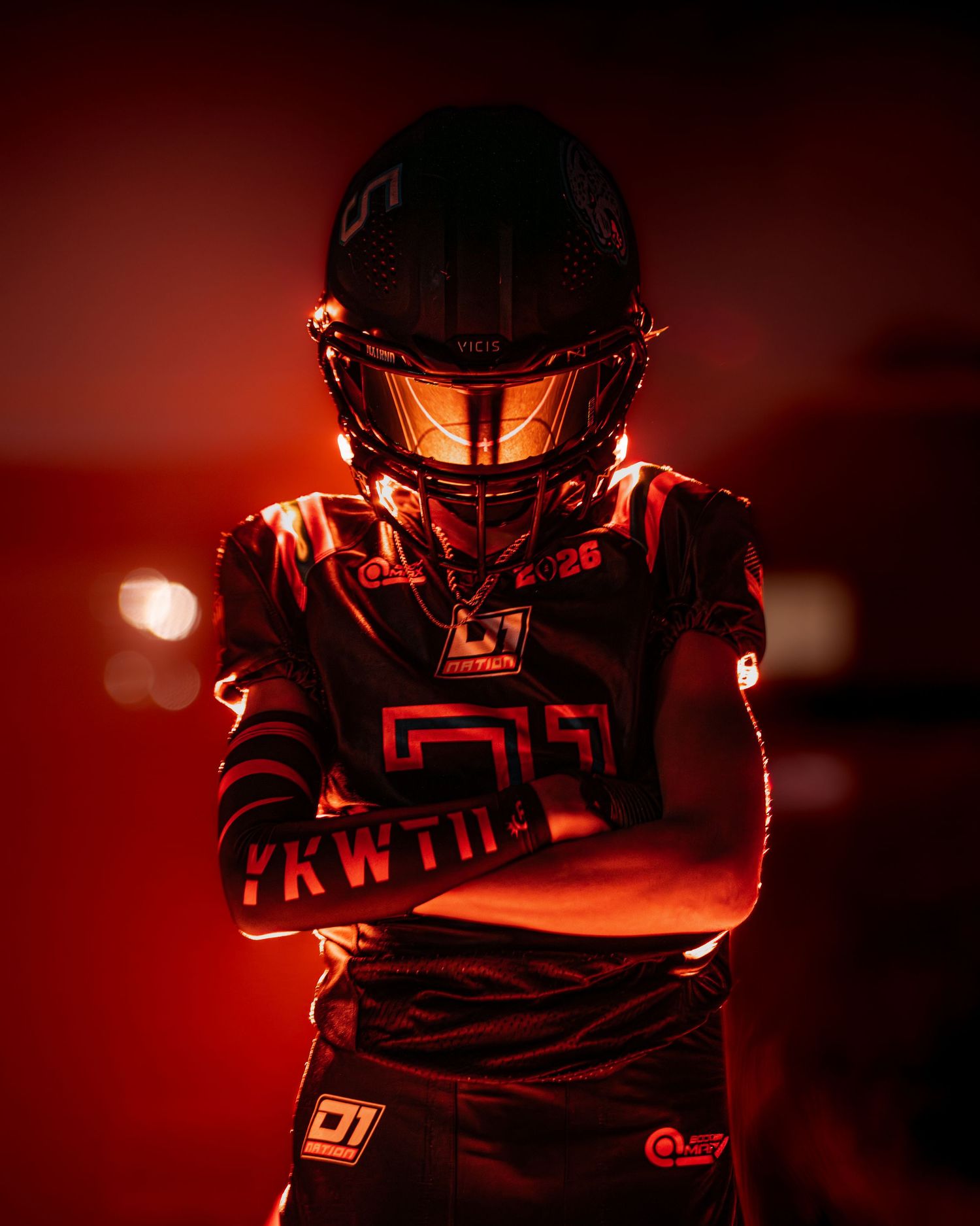 Dramatic silhouette of a football player in red lighting against dark background creates an intense athletic atmosphere.