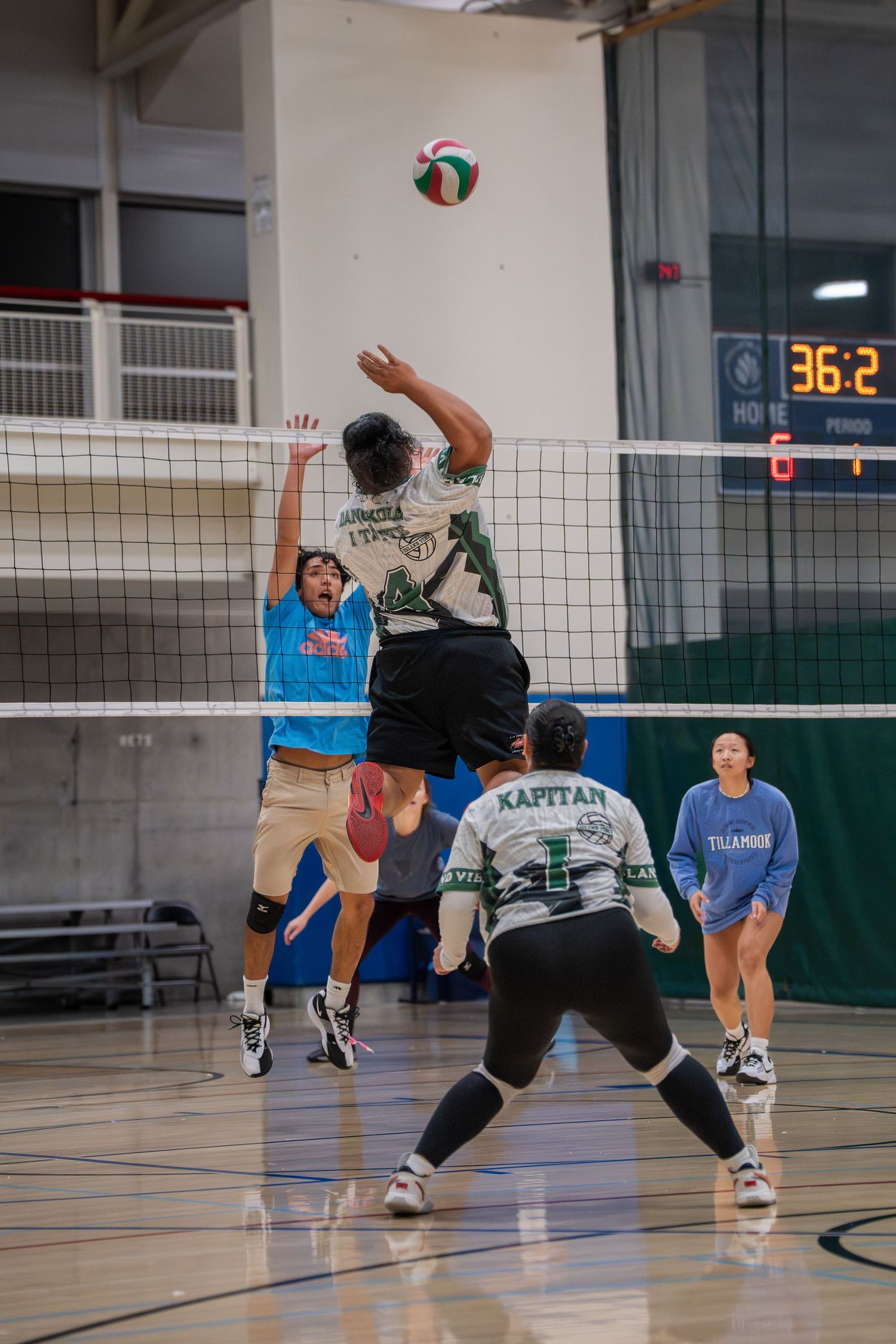 Indoor volleyball players compete at the net during an intense match.