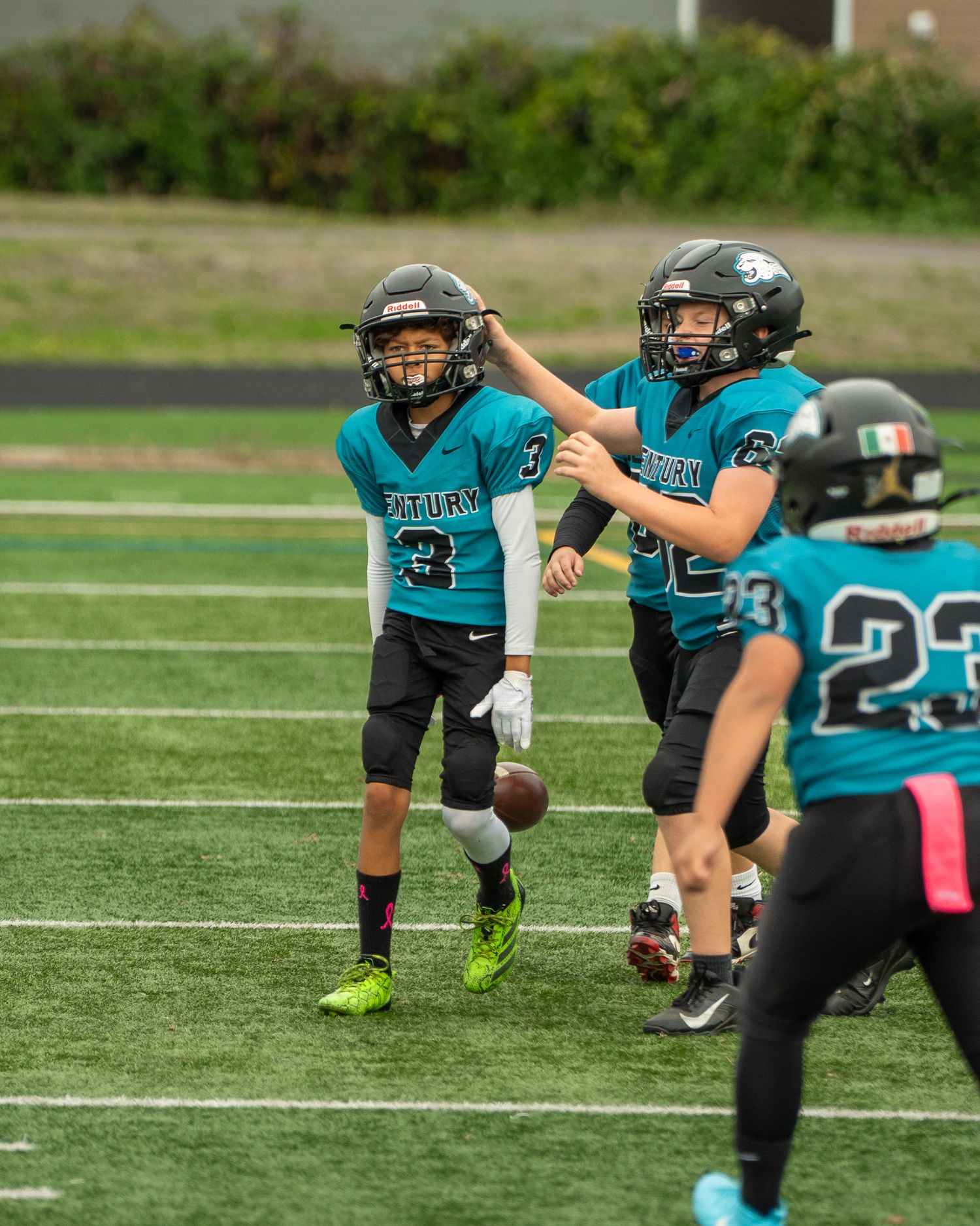 Youth football team in teal uniforms practices field goal formations.