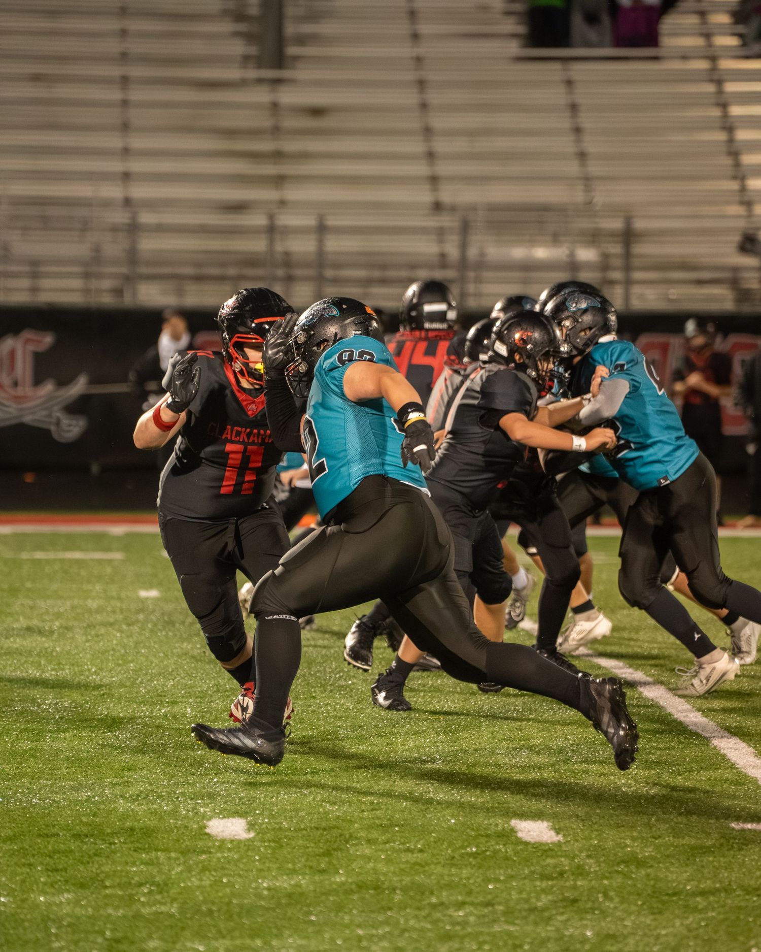 Football players from opposing teams clash during an intense play on the field.