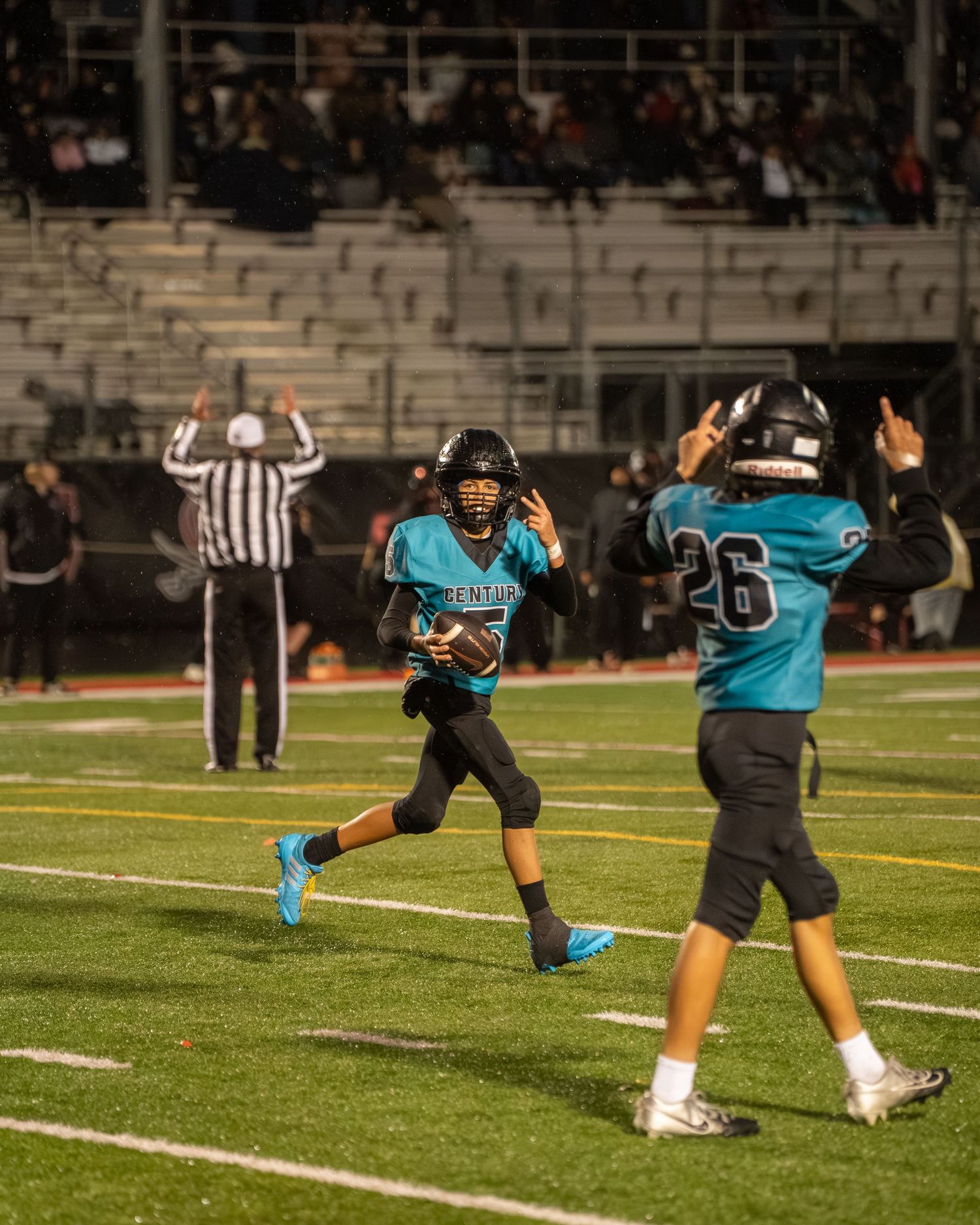 Football players celebrate a touchdown as referee signals score in the background.