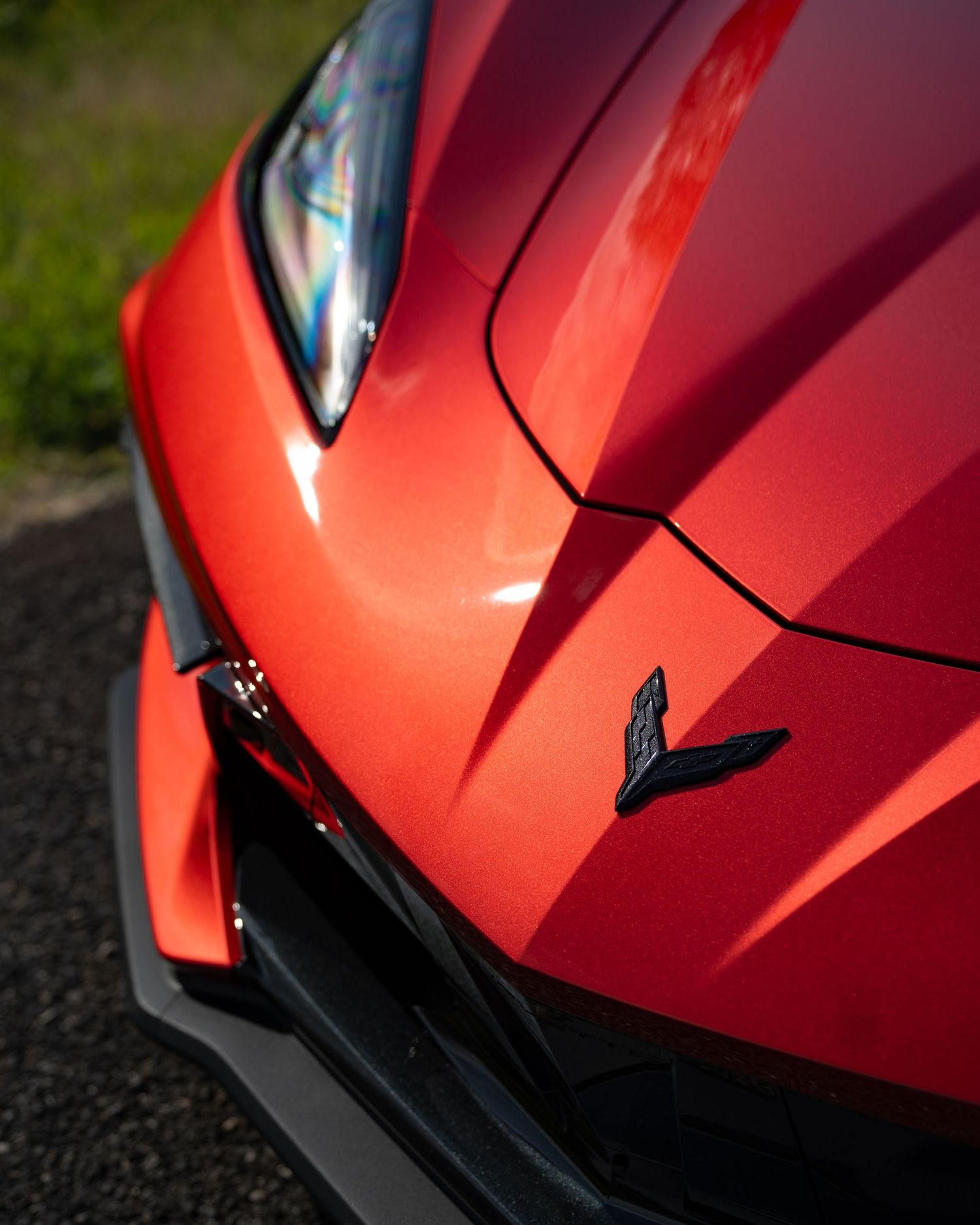Close-up detail of a red metallic supercar hood showing sharp body lines and curves.