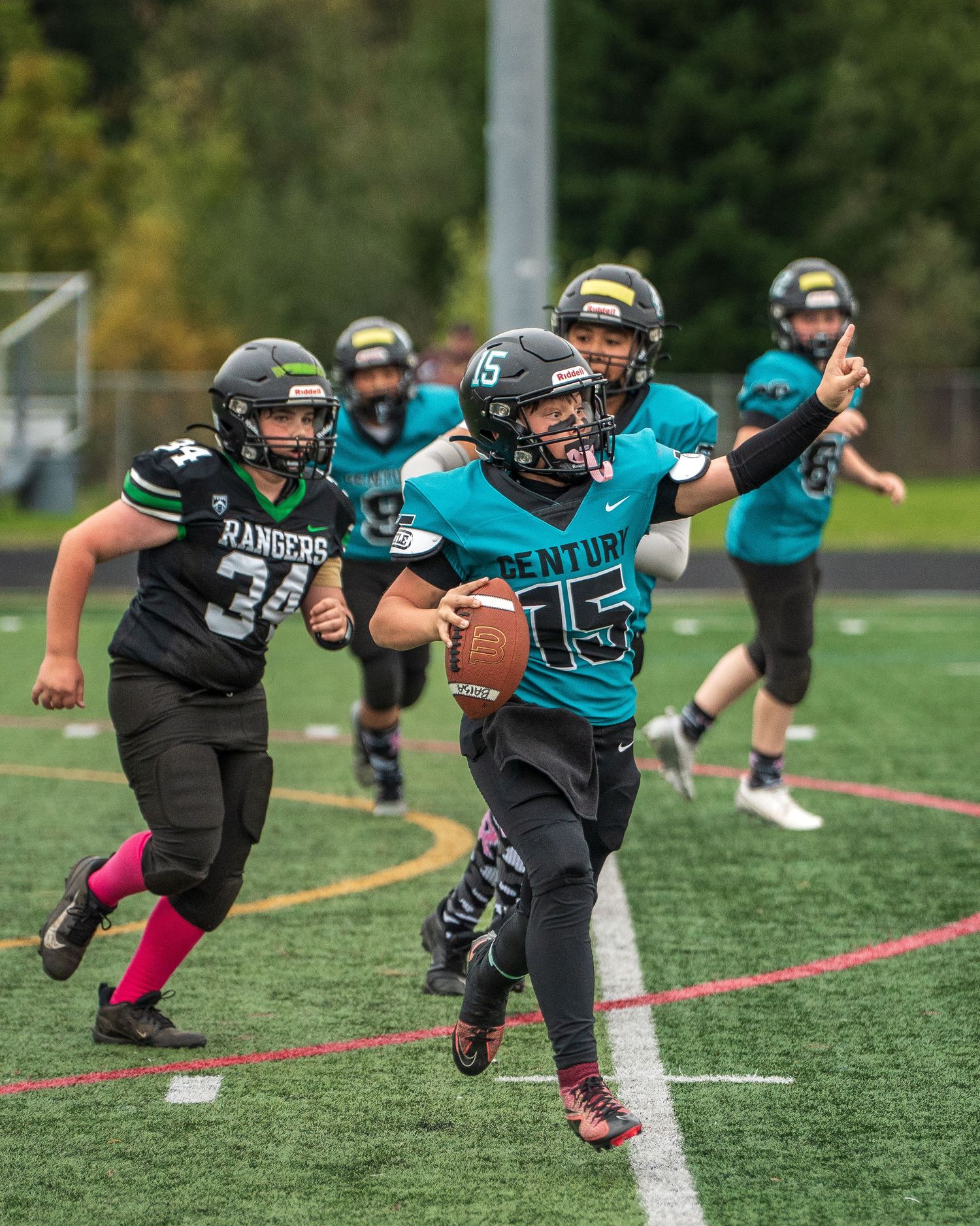 Football players in teal and black uniforms practice diving catches on the field.