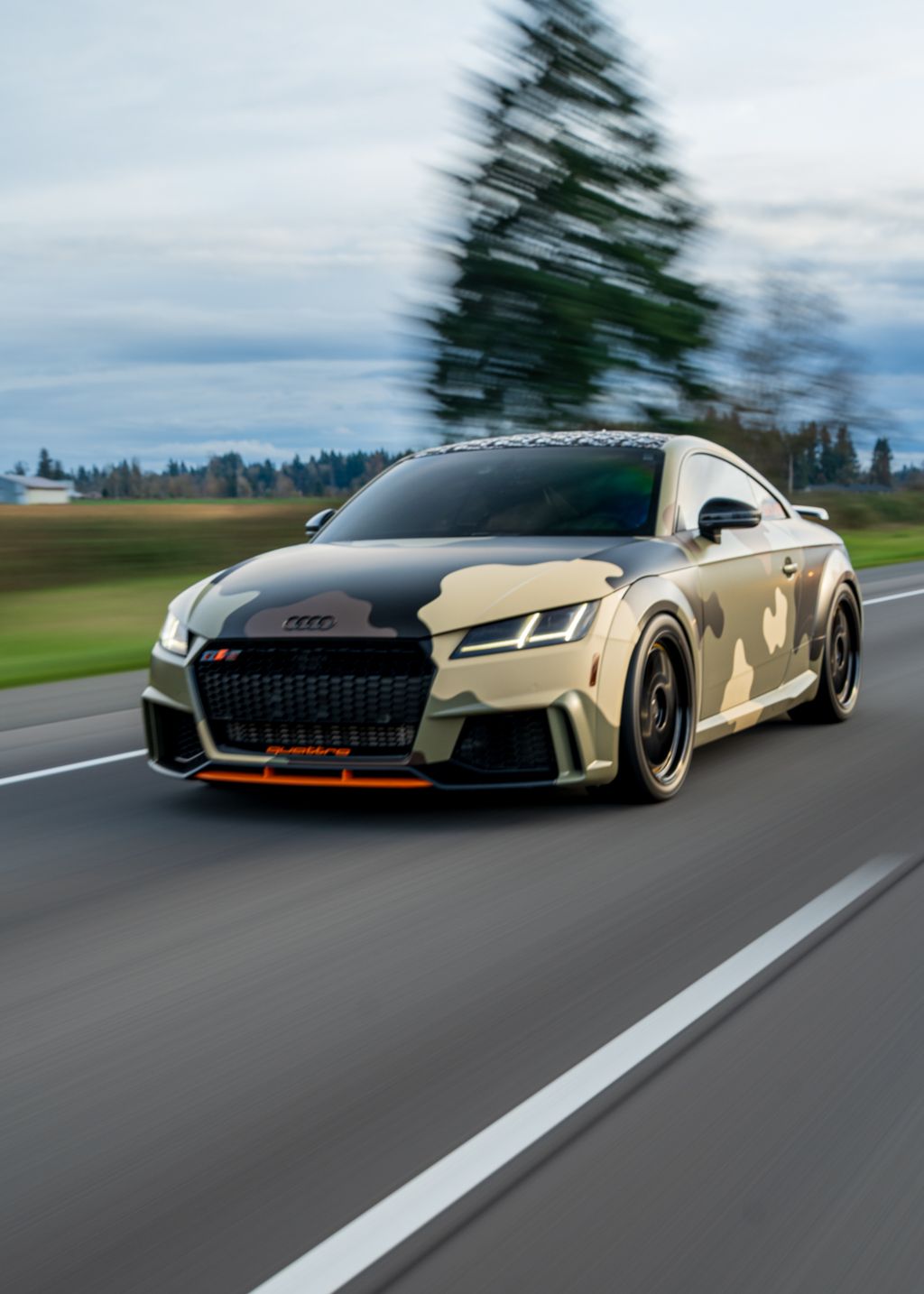 Lowered Audi R8 sports cars in desert camo wrap driving on a highway.