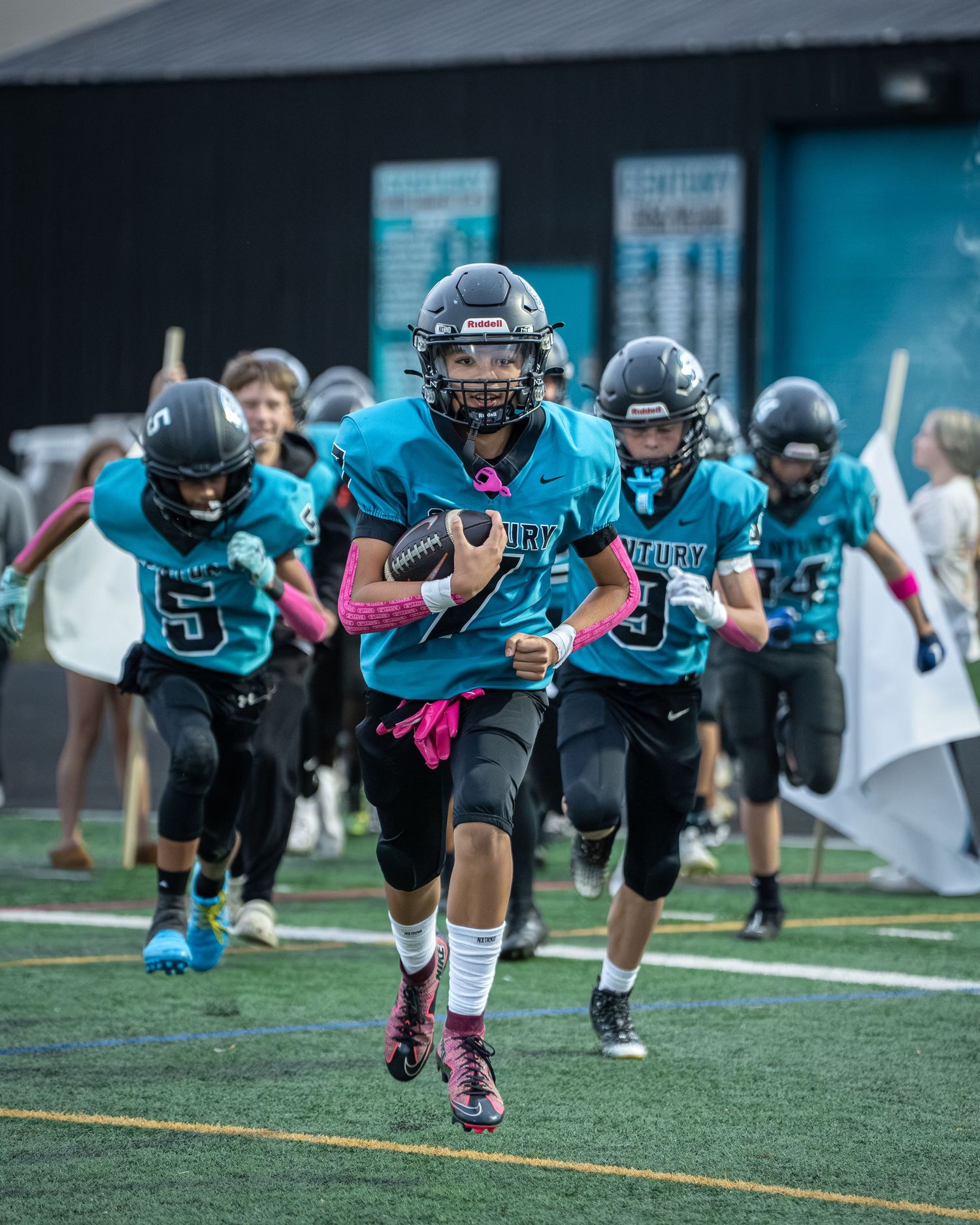 Football team performing synchronized diving drill on artificial turf field.