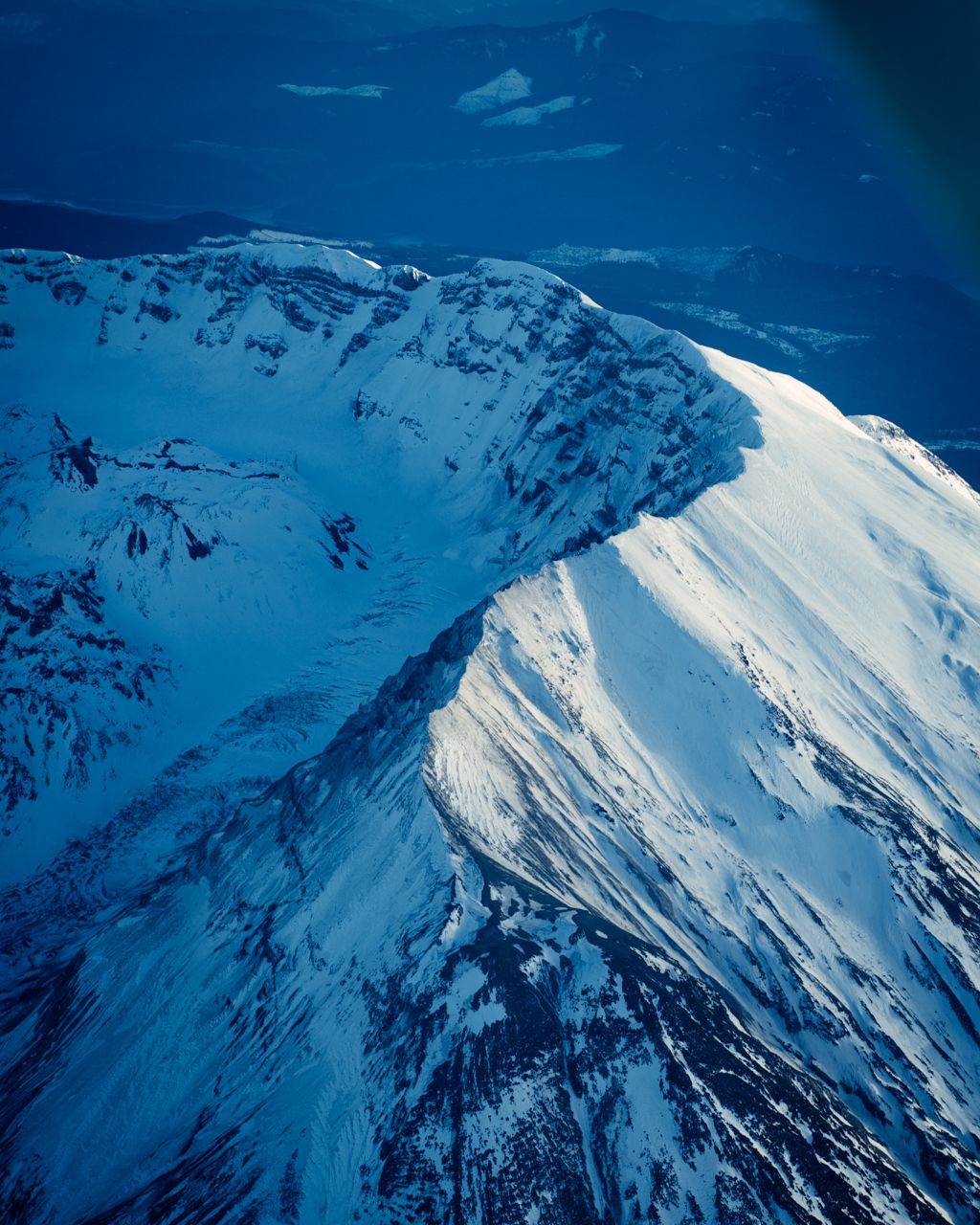 Snow-covered mountain peaks against deep blue sky in dramatic winter landscape.
