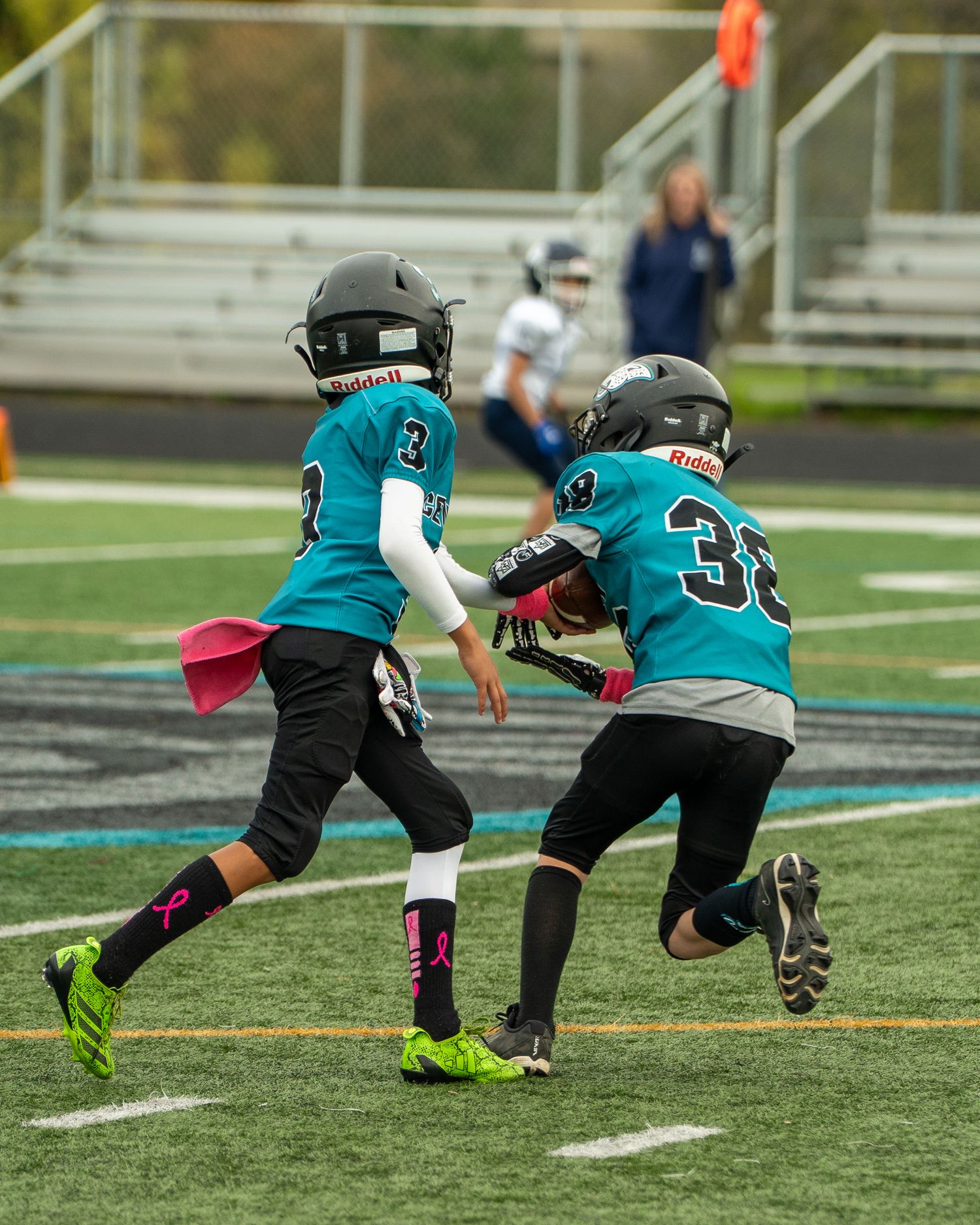 Players in teal uniforms perform diving drills on artificial turf.