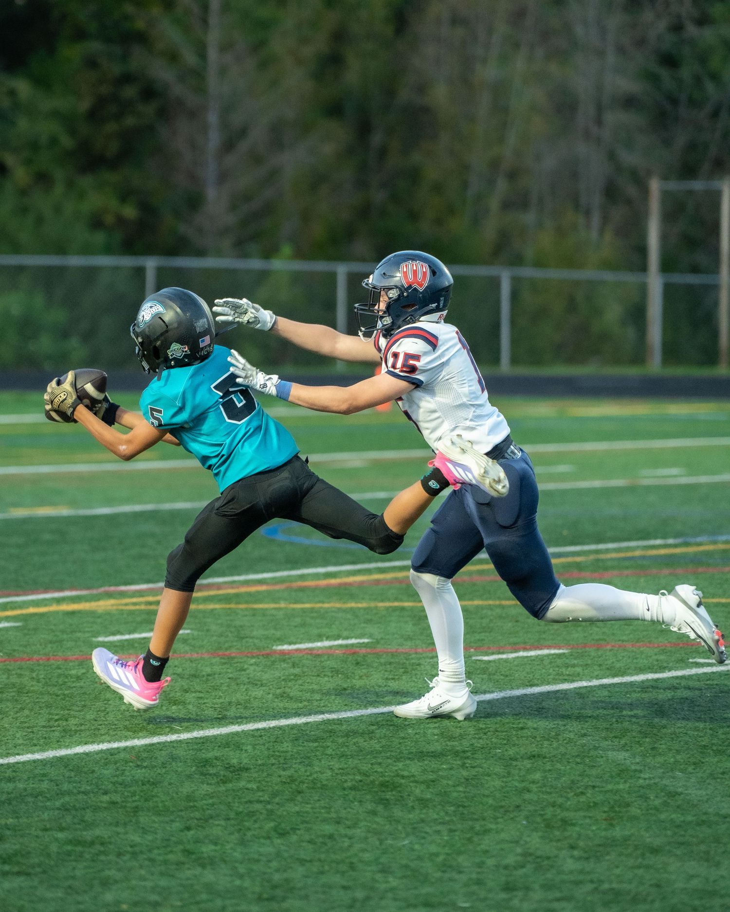 Players demonstrate diving tackle techniques during football practice on the turf field.