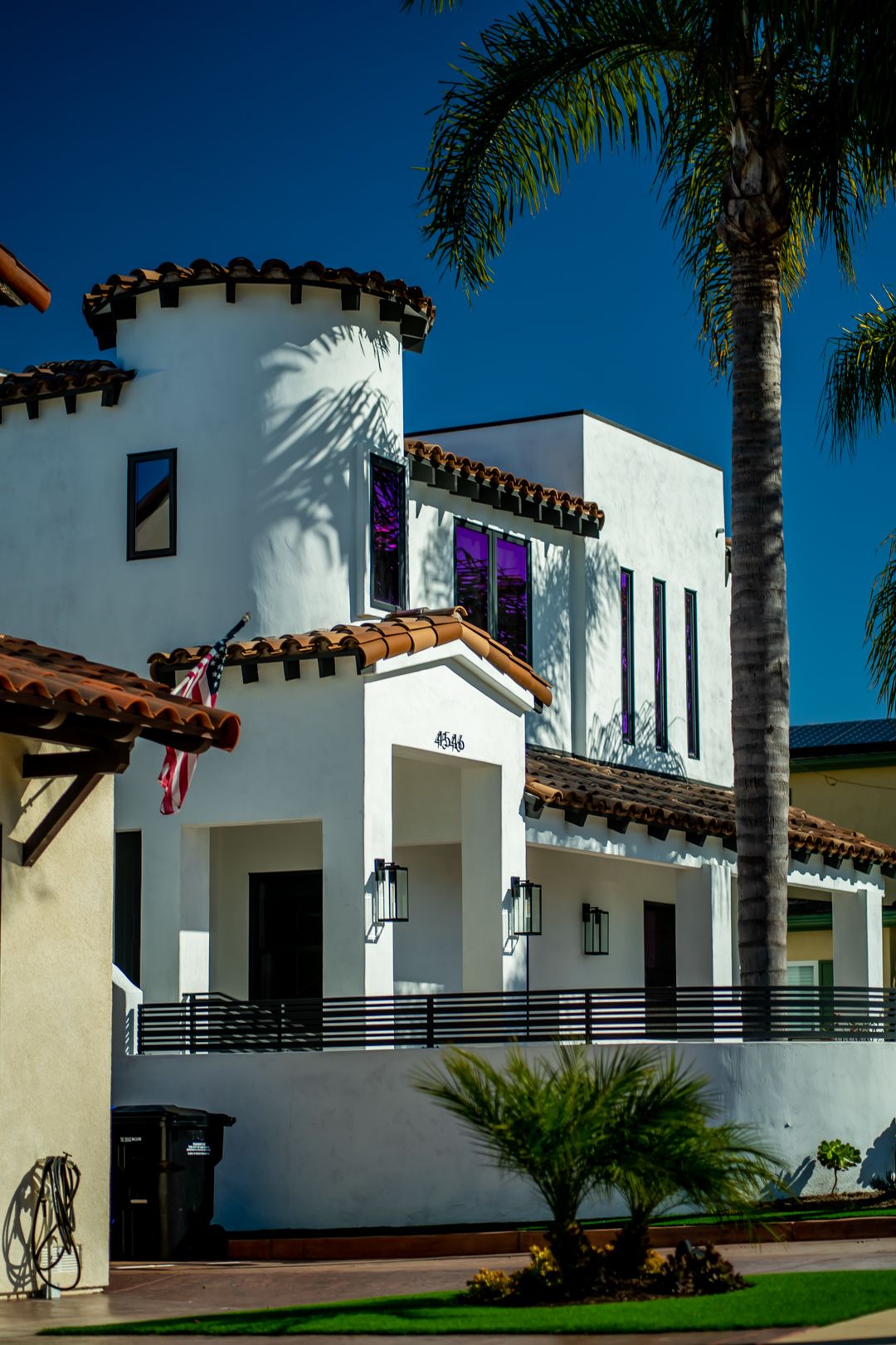 White Spanish-style buildings with turrets and palm trees under bright blue sky.