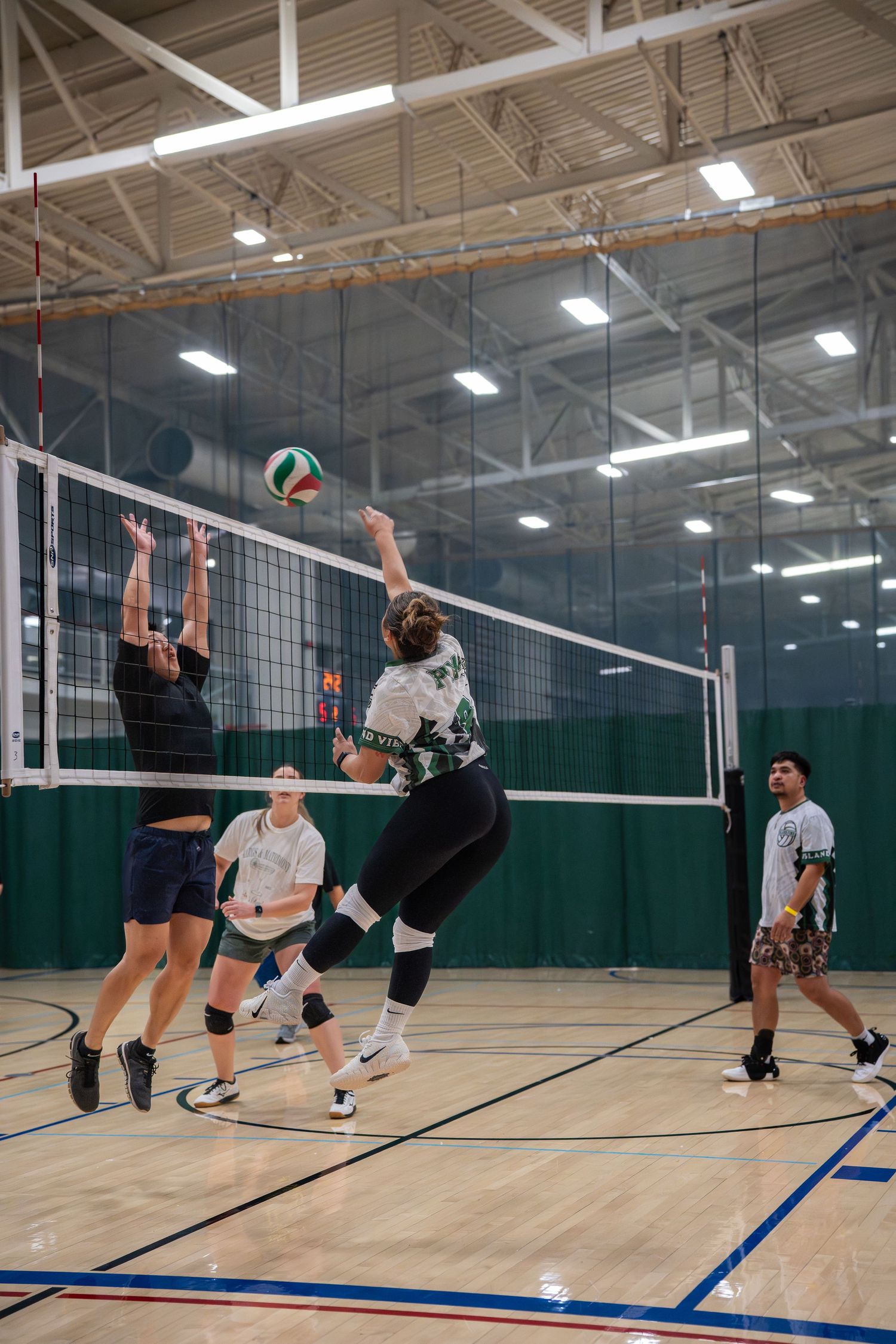Indoor volleyball players in action at the net during a competitive match.