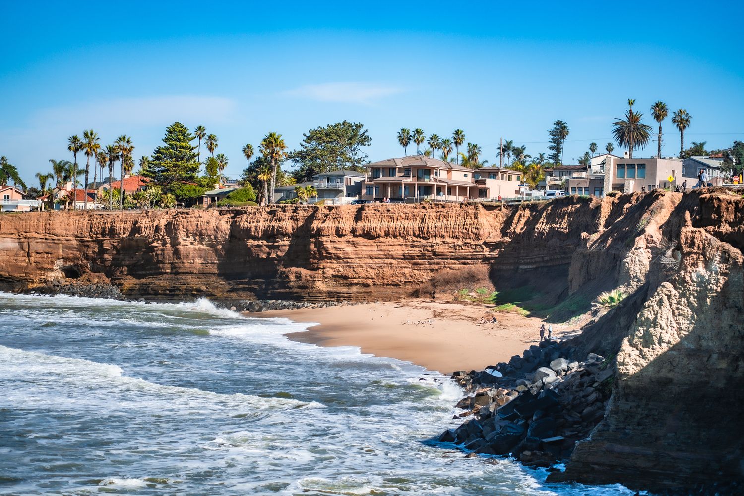Rocky coastal cliffs and sandy beaches with crashing waves along the shoreline.