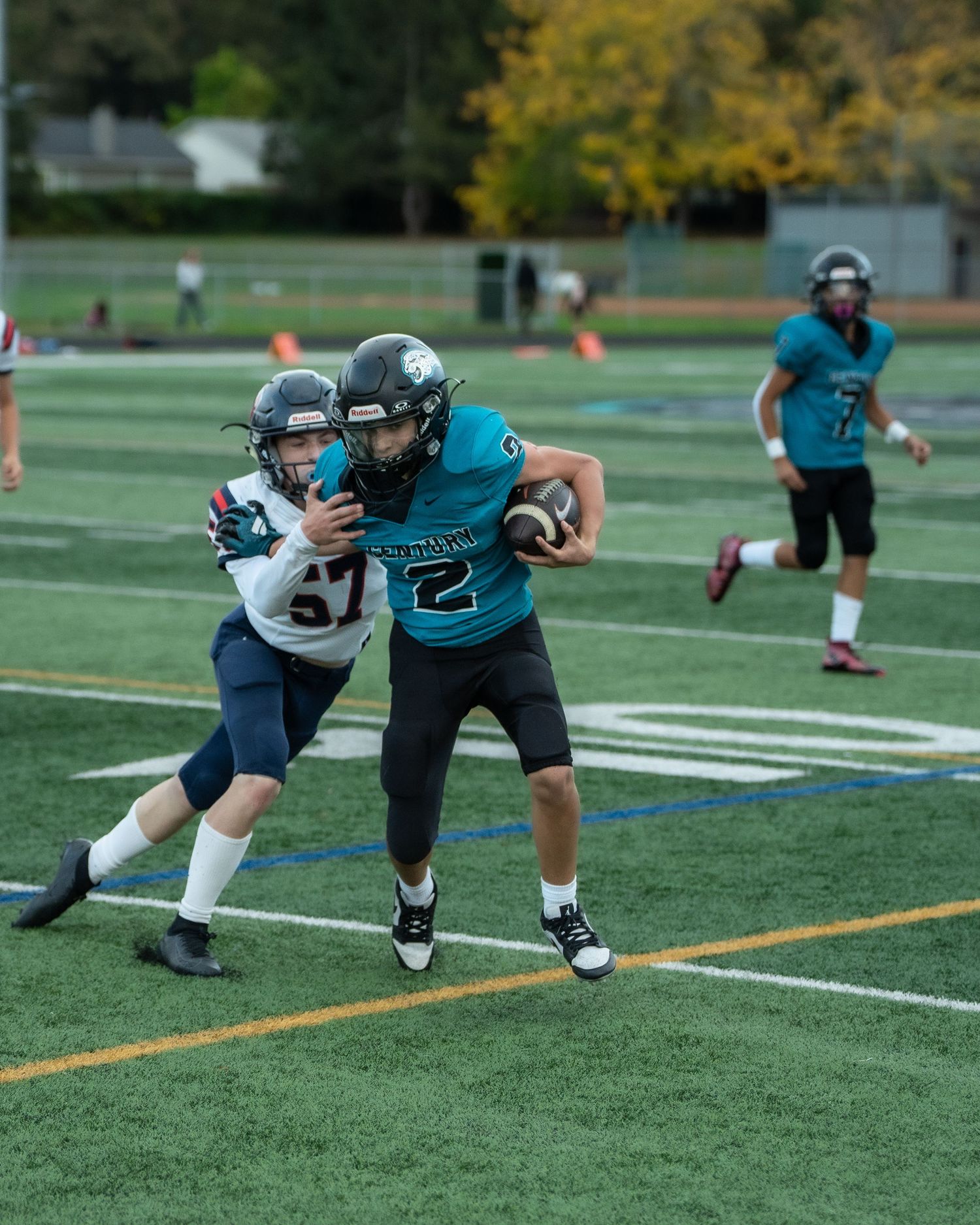 Players practicing defensive moves on football field with artificial turf.
