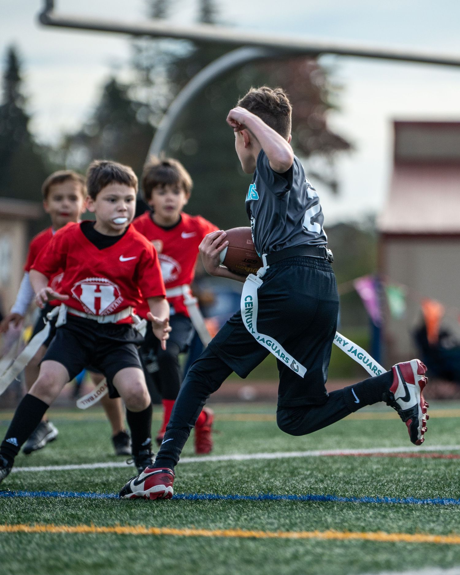 Youth football players performing diving drills on an artificial turf field.