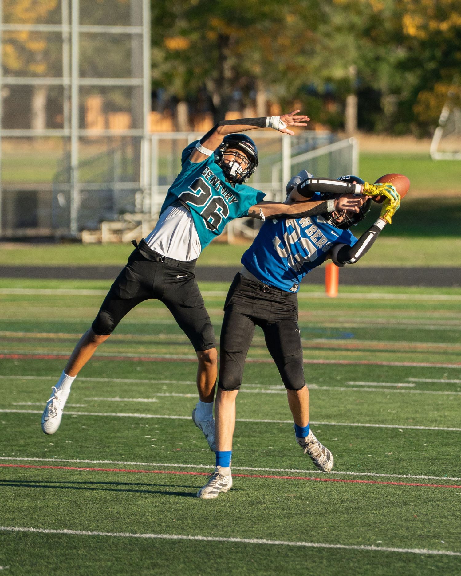 Players in teal uniforms practice diving techniques on the football field.