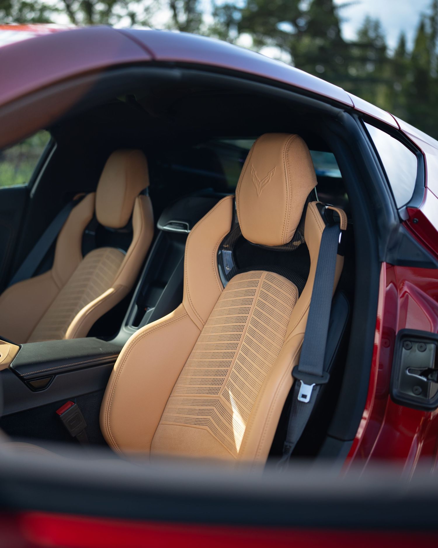 Luxurious tan leather sports seats inside a red supercar interior.