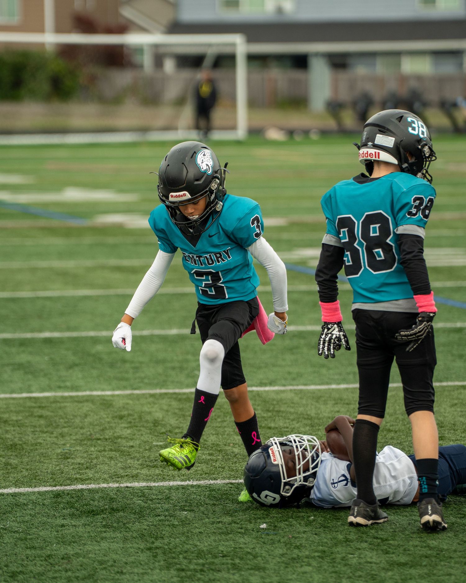 Youth football team practices defensive formations on grass field.