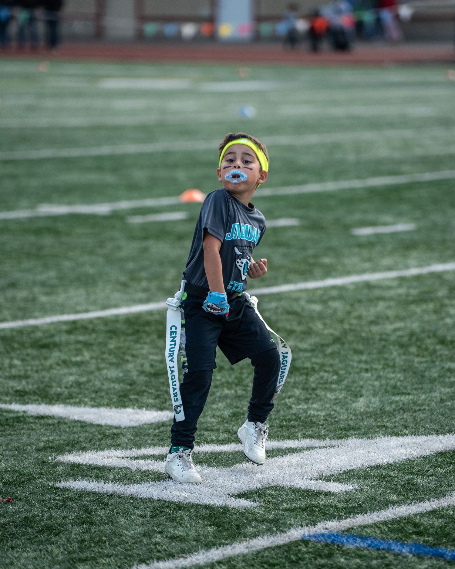 Youth athletes practicing agility drills on a football field with white yard lines.