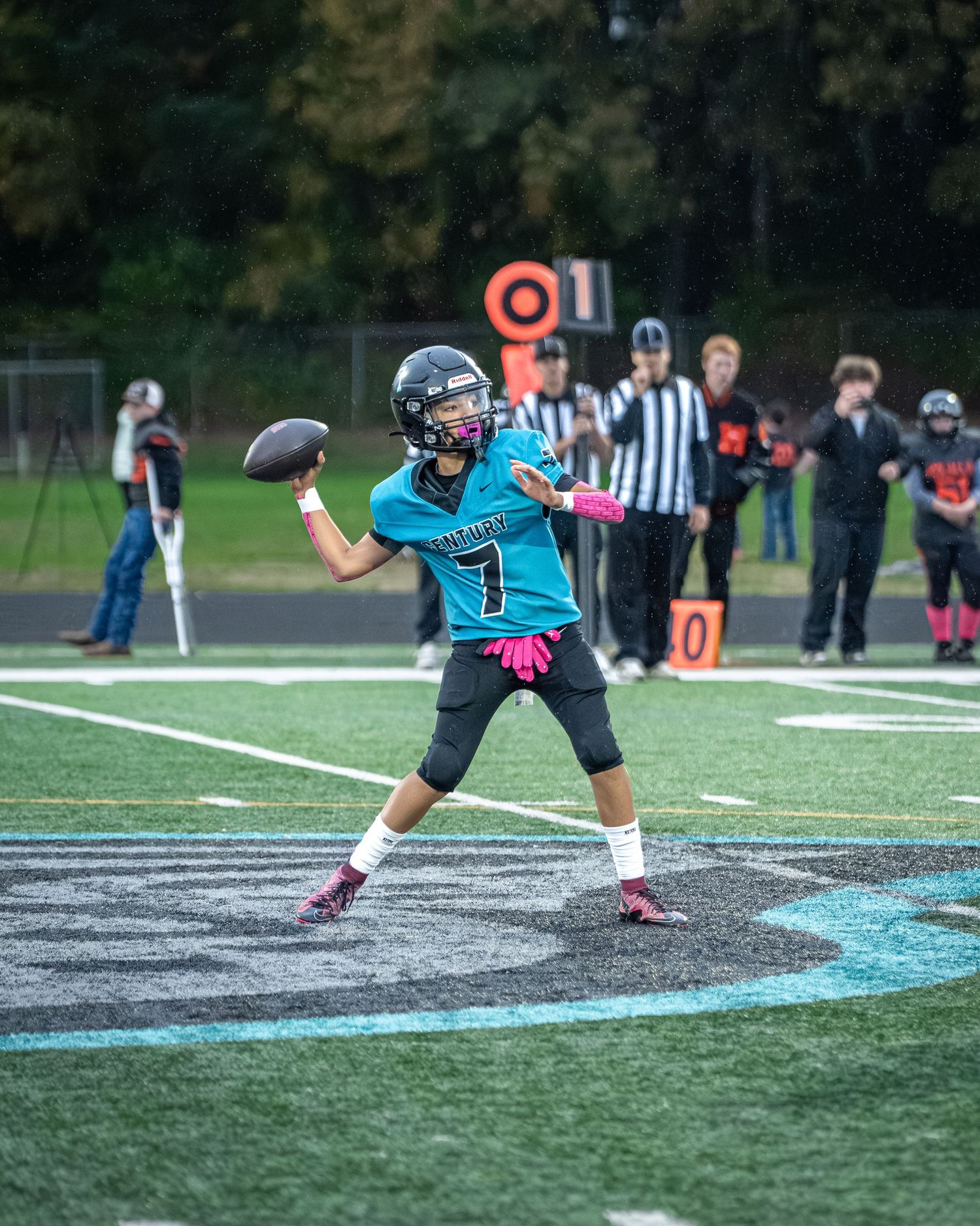 Football player in teal jersey demonstrates footwork drill on marked field.