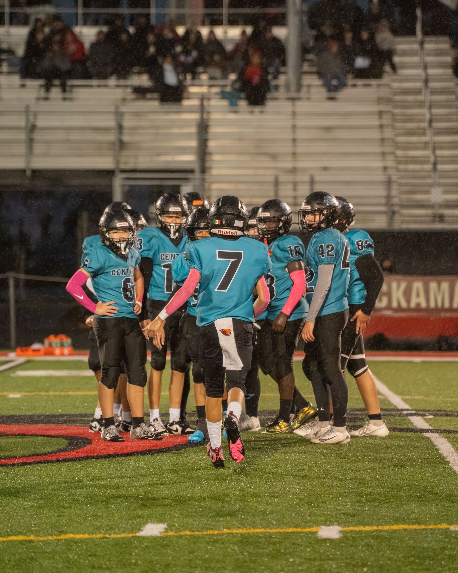 Football team in teal jerseys lined up in formation on field during game.